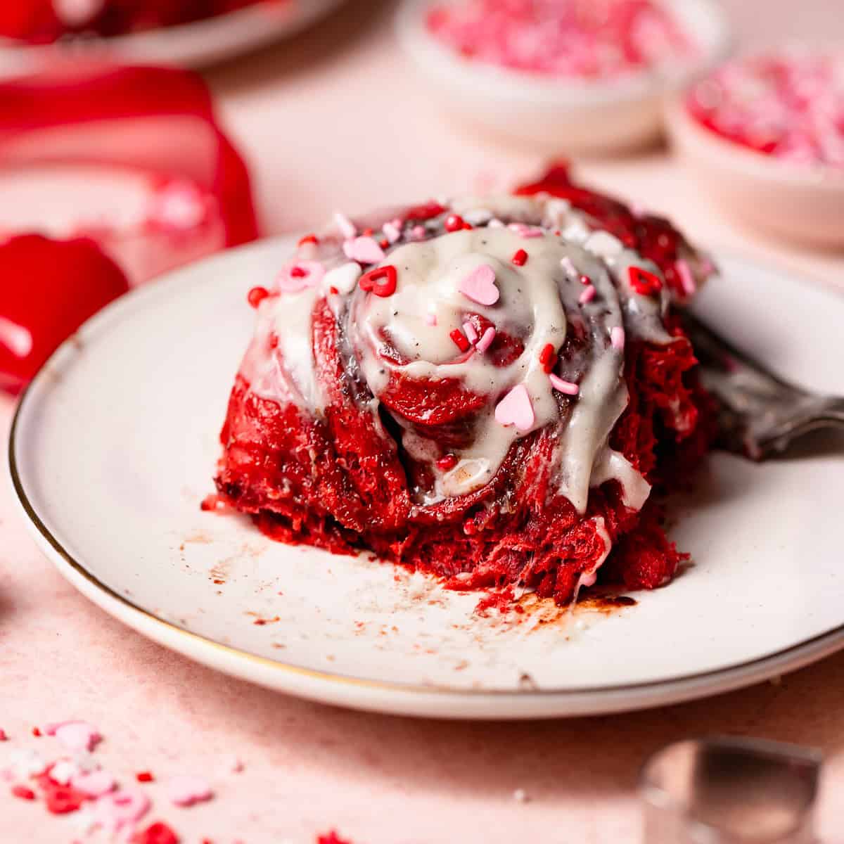 A red velvet bun on a plate with a bite missing to show the gooey texture.