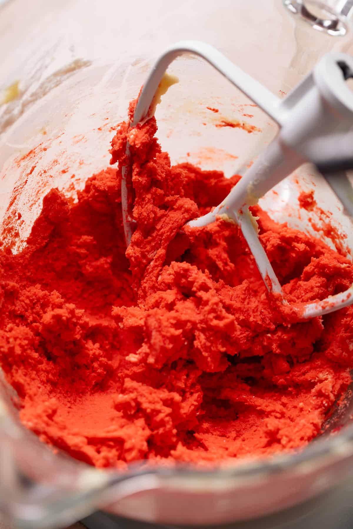 Red sugar cookie dough in a mixing bowl.