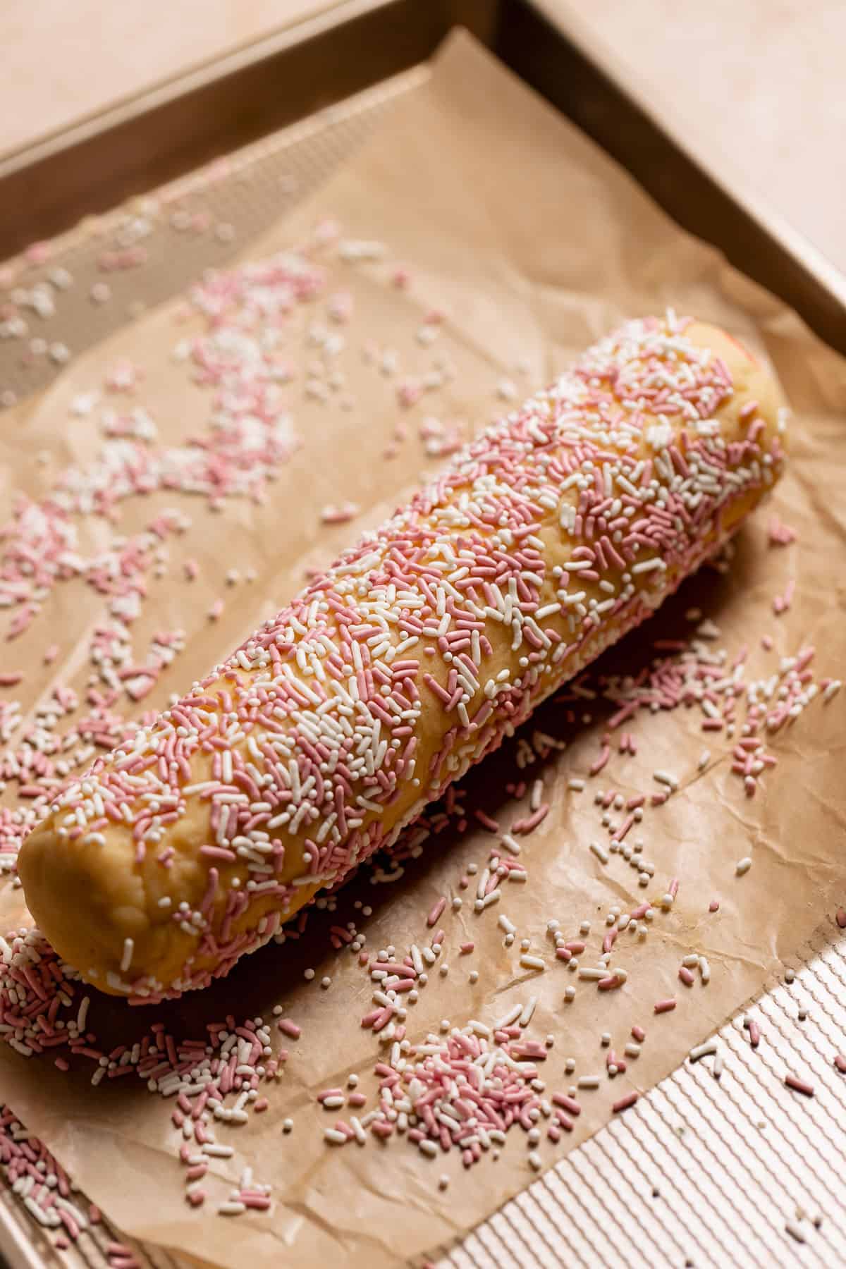 The log of sugar cookie dough rolled in pink and white jimmy sprinkles.