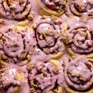 Blackberry rolls with berry icing on top in a baking pan.