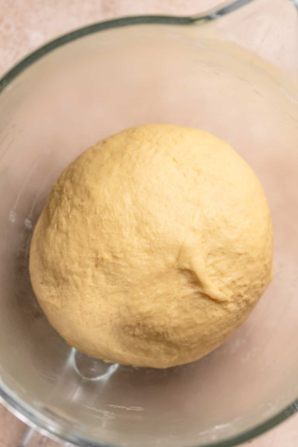 The cinnamon roll dough ball in a bowl resting.