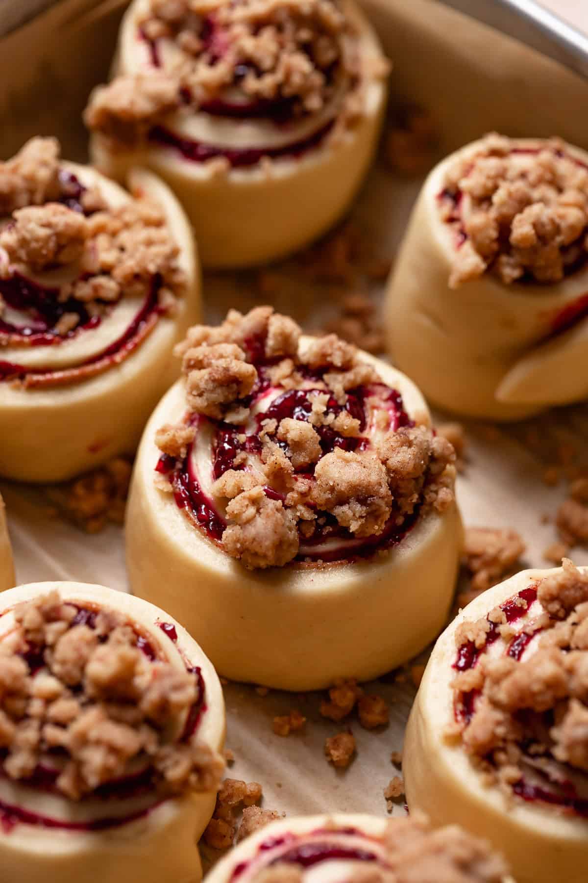 A cinnamon roll with crumb topping on top before baking.