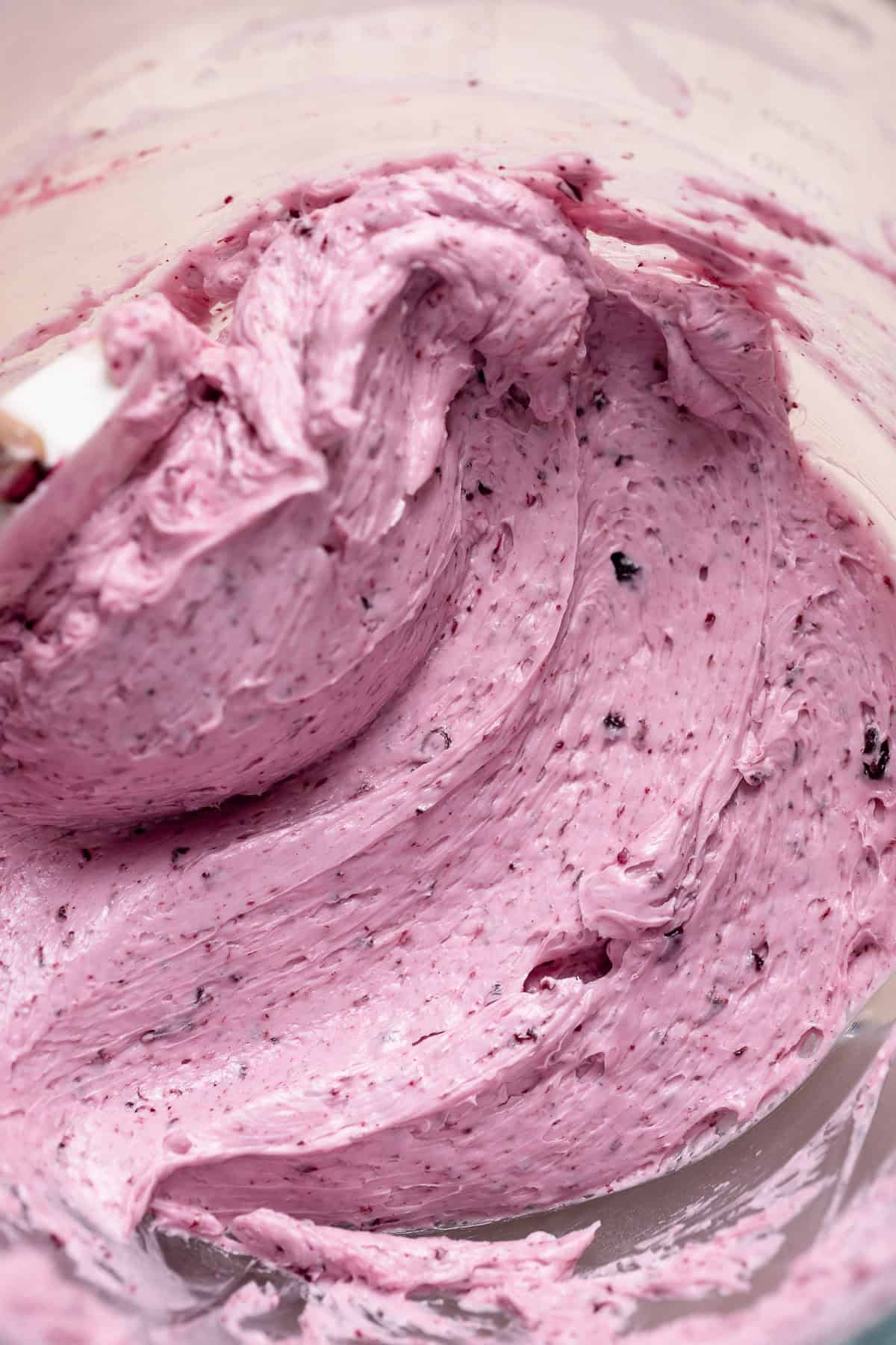 Blueberry frosting in a glass mixing bowl.