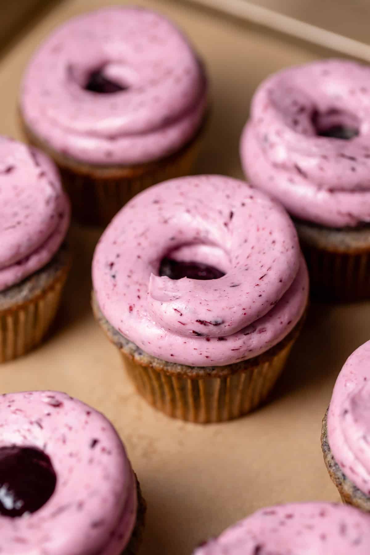 Cupcakes on a baking tray with frosting swirled on top.