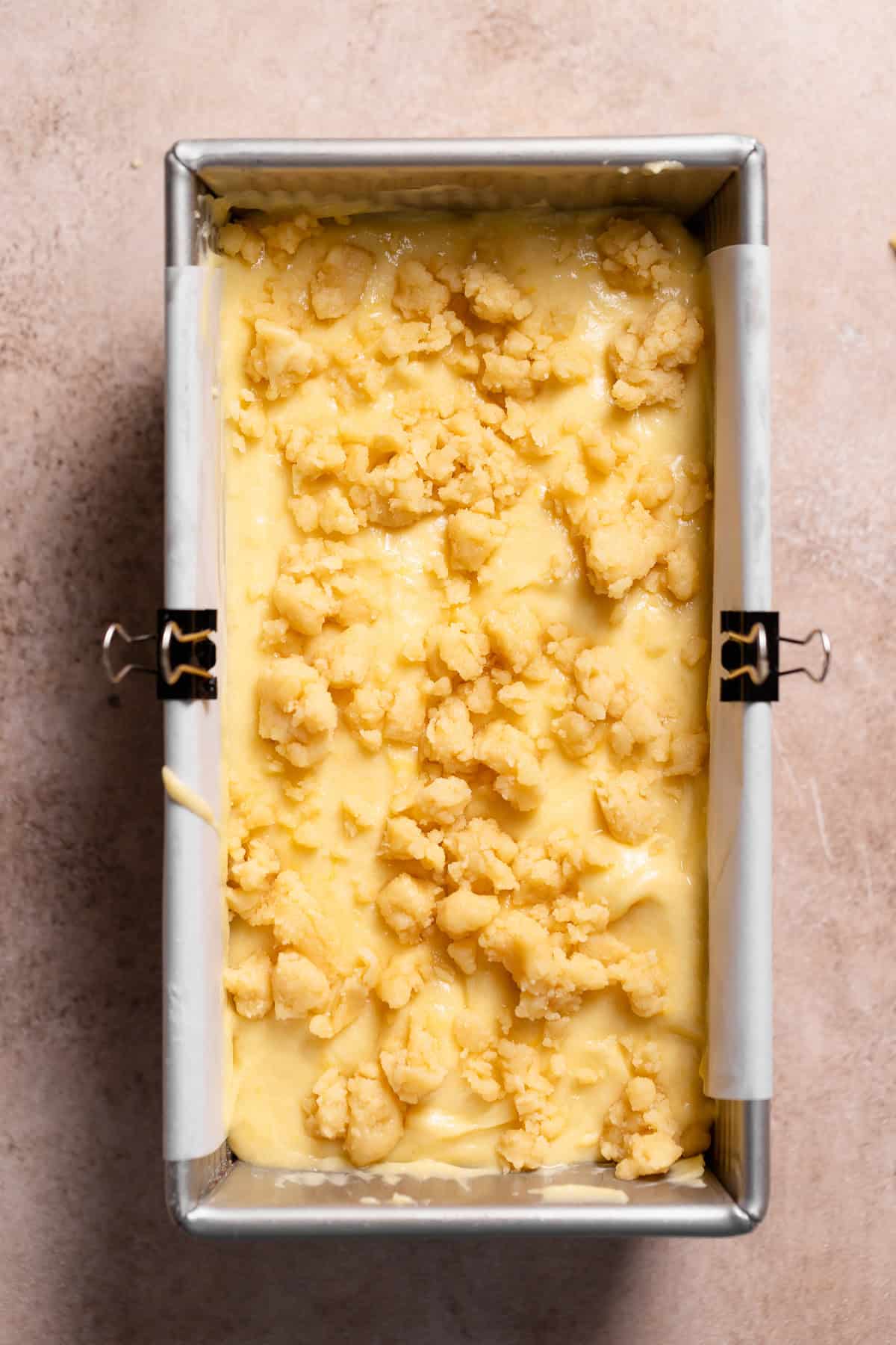 A loaf pan with the lemon cake batter and crumb topping before baking.