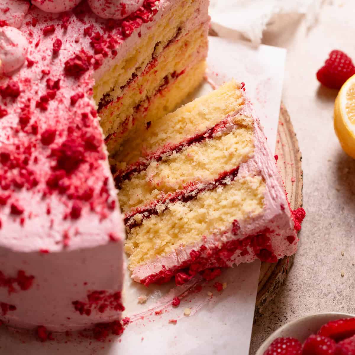 A slice of lemon cake with raspberry filling on its side.