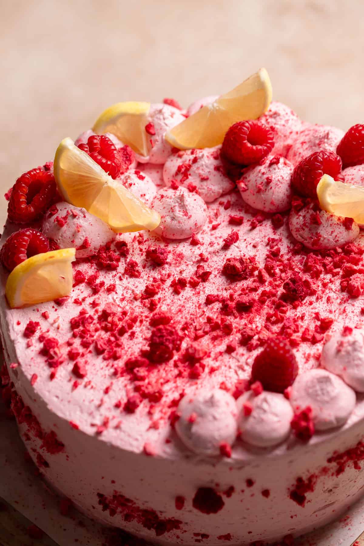 The entire lemon raspberry cake with fresh lemon slices, raspberries, and freeze-dried raspberries on top.