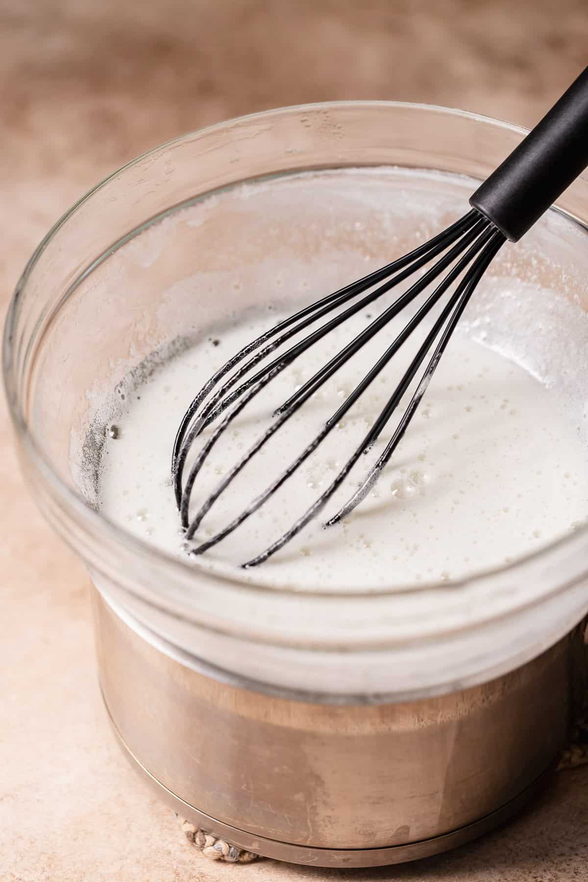 A bowl of meringue over a double boiler.