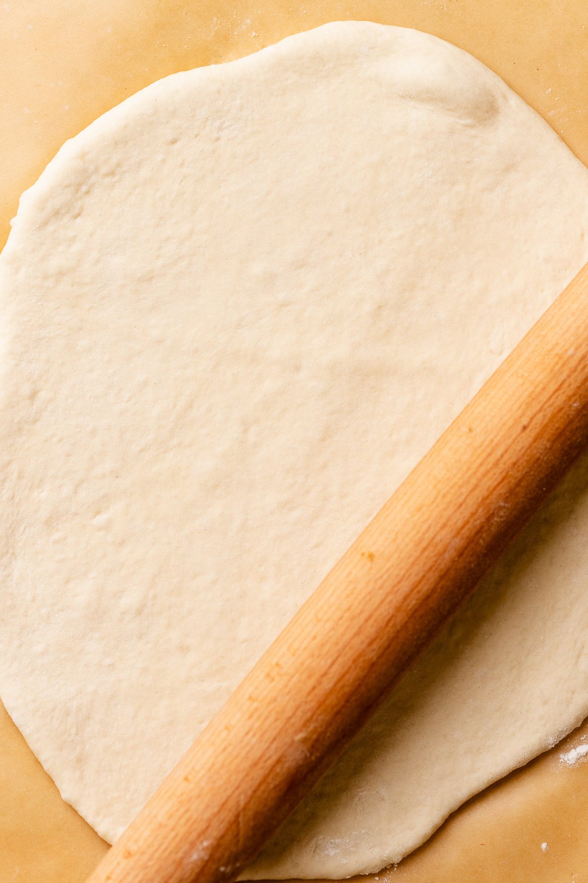A rolling pin rolling out the pizza crust.