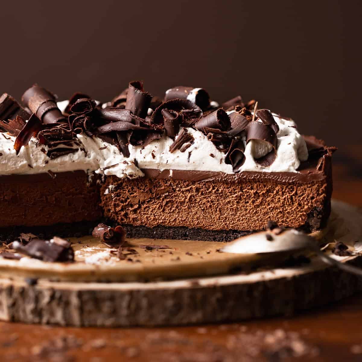 Chocolate mousse pie with an oreo crust and homemade whipped cream on top on a wooden platter.