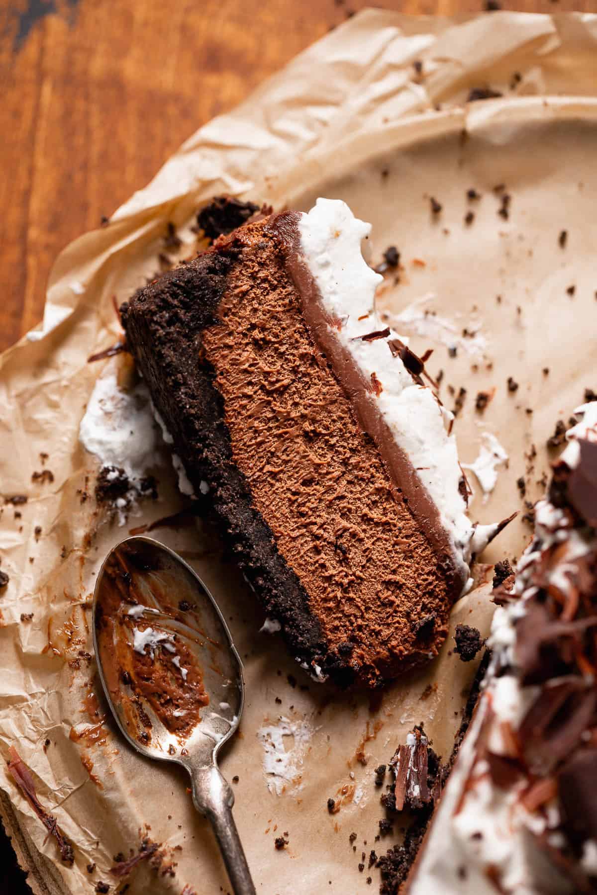 A slice of mousse pie with oreo crust on brown parchment paper