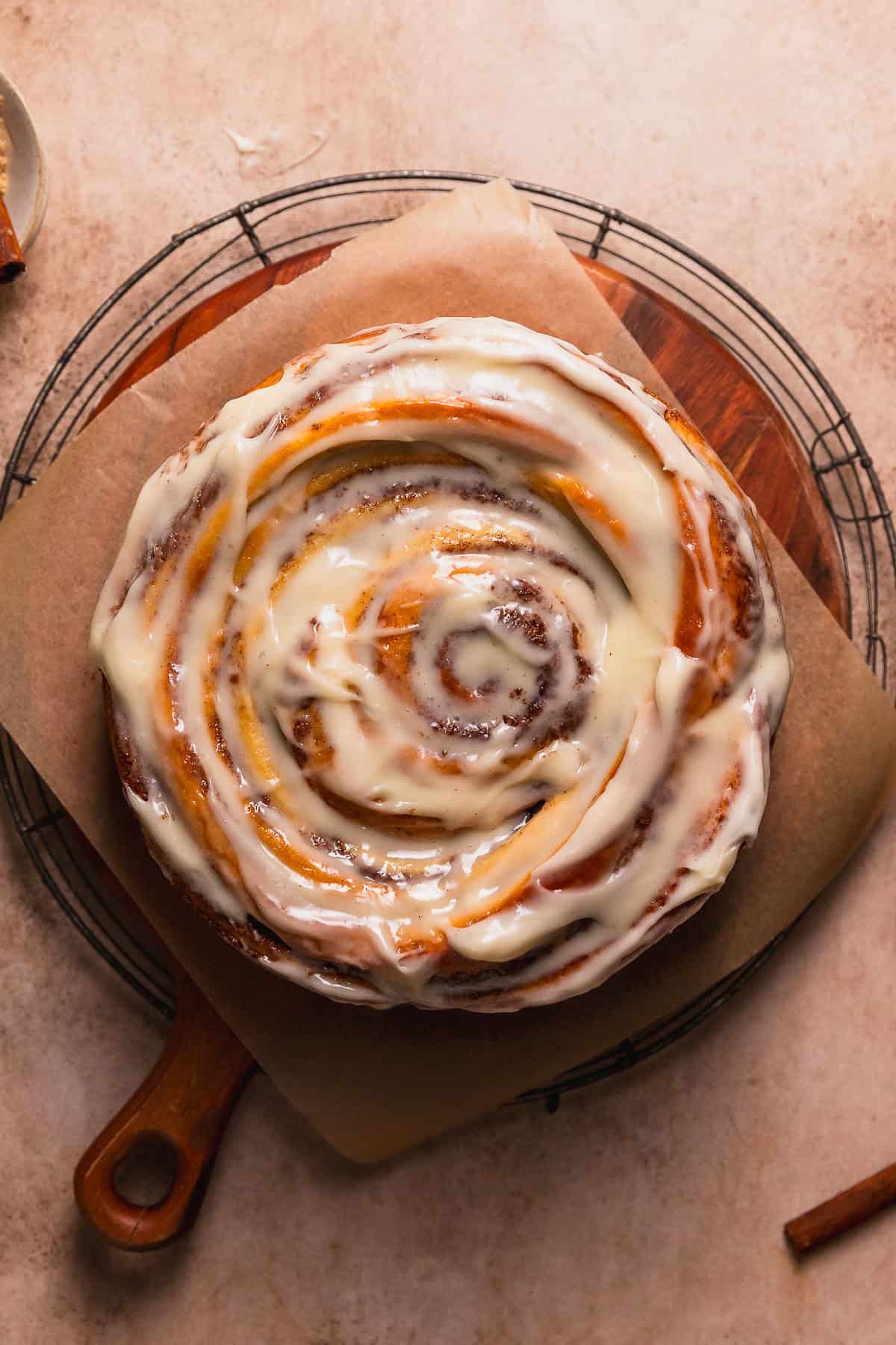Cinnamon swirl cake on a wooden platter after being frosted.