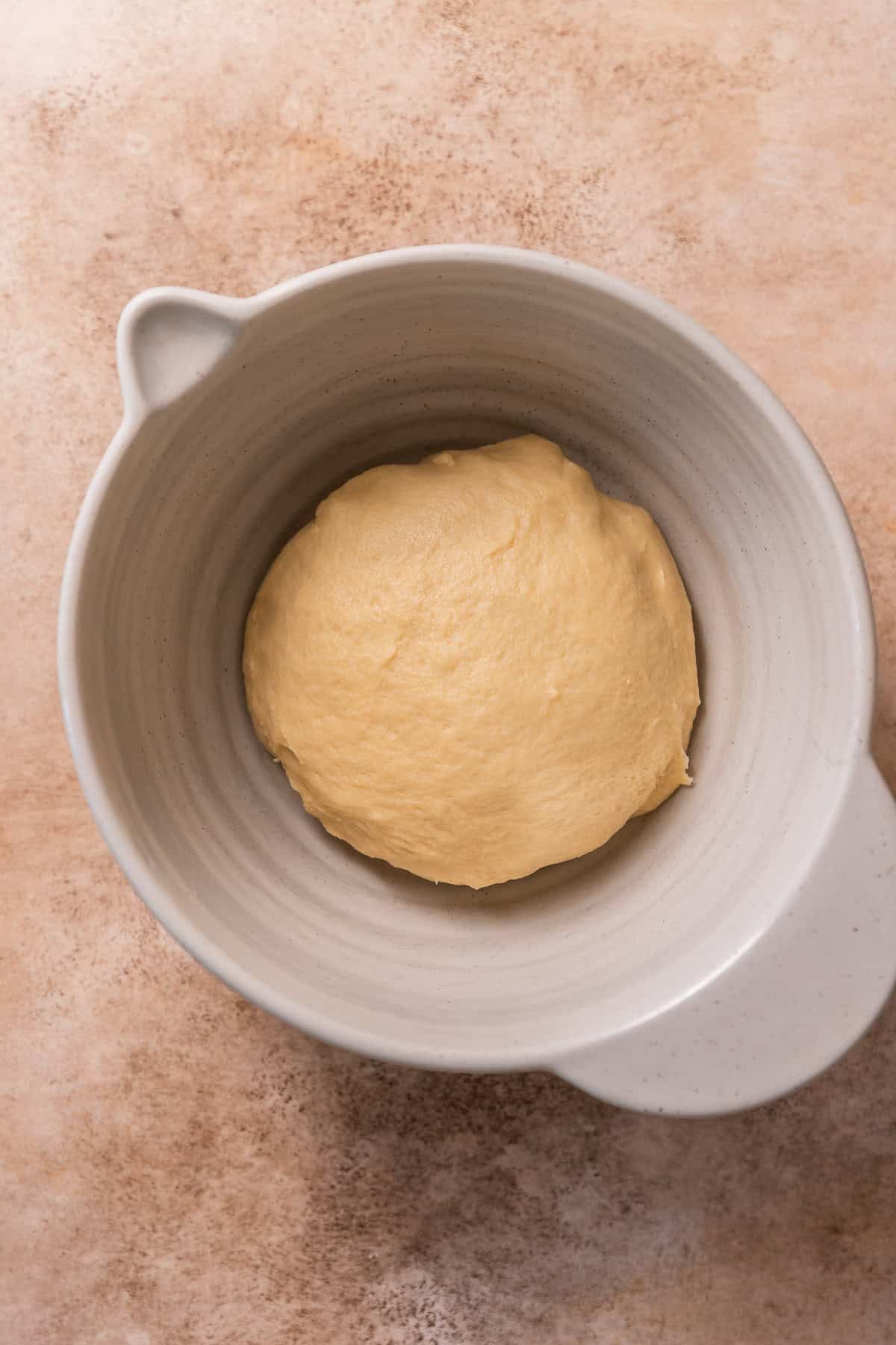 The cinnamon roll dough in a bowl, resting.