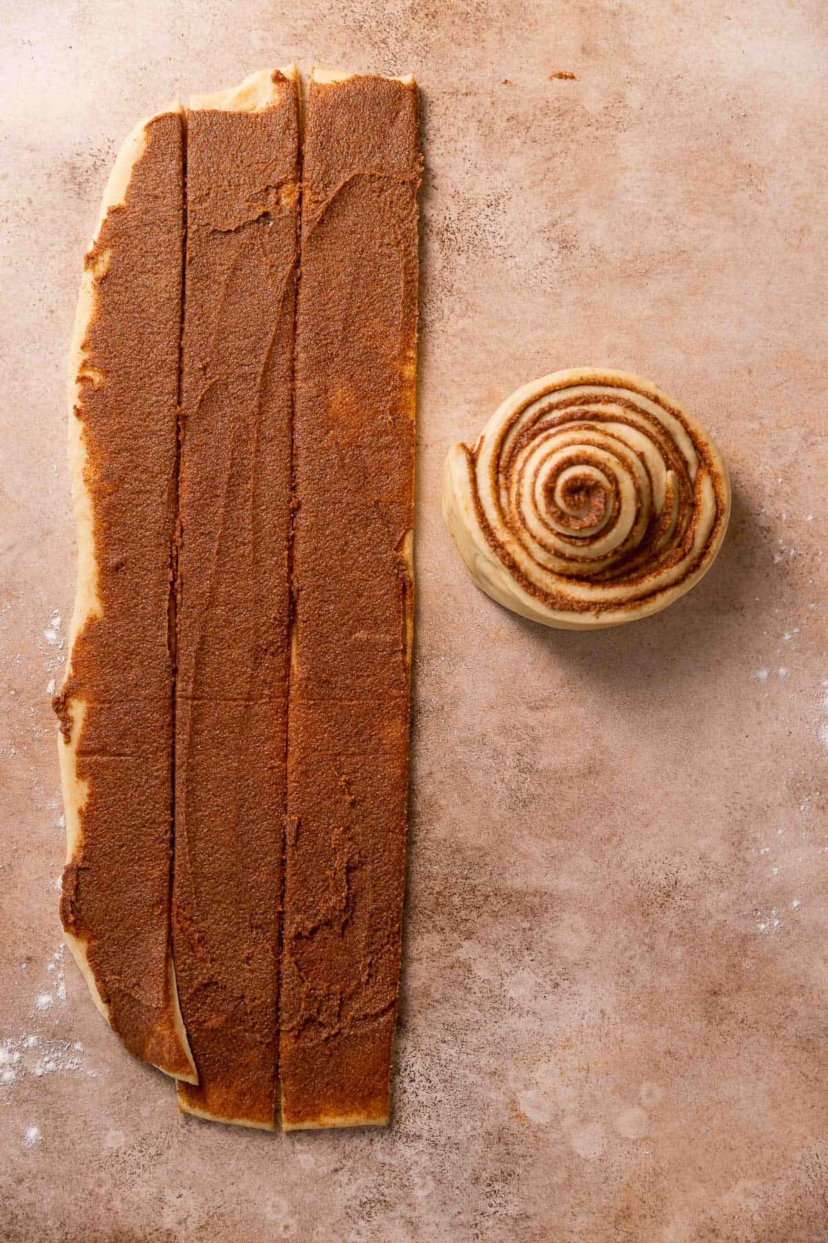 The strips of cinnamon sugar dough being rolled up together into one giant bun.