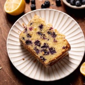 A slice of lemon blueberry cake on a white plate.