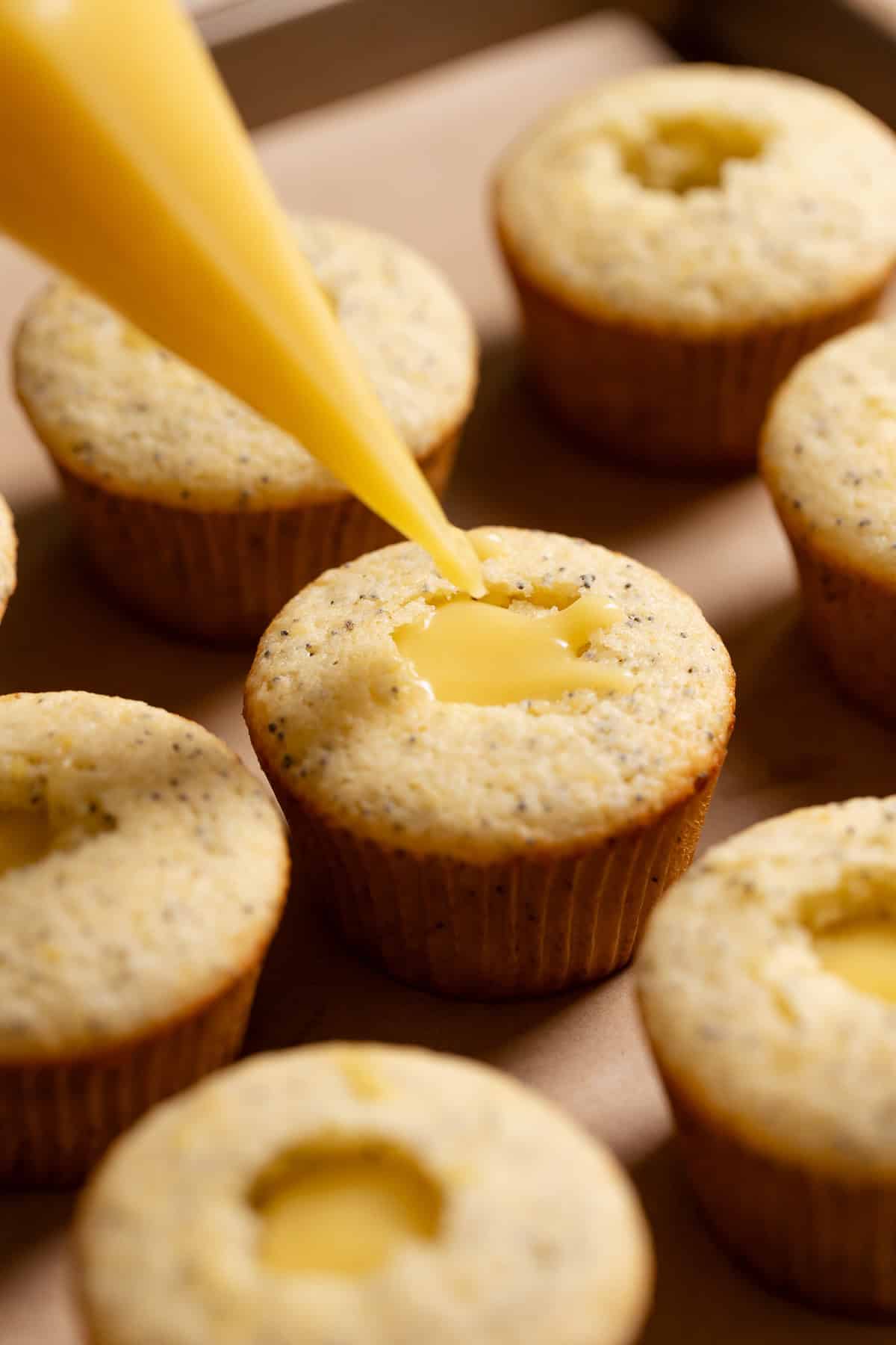 A piping bag filling the lemon cupcakes with lemon curd.