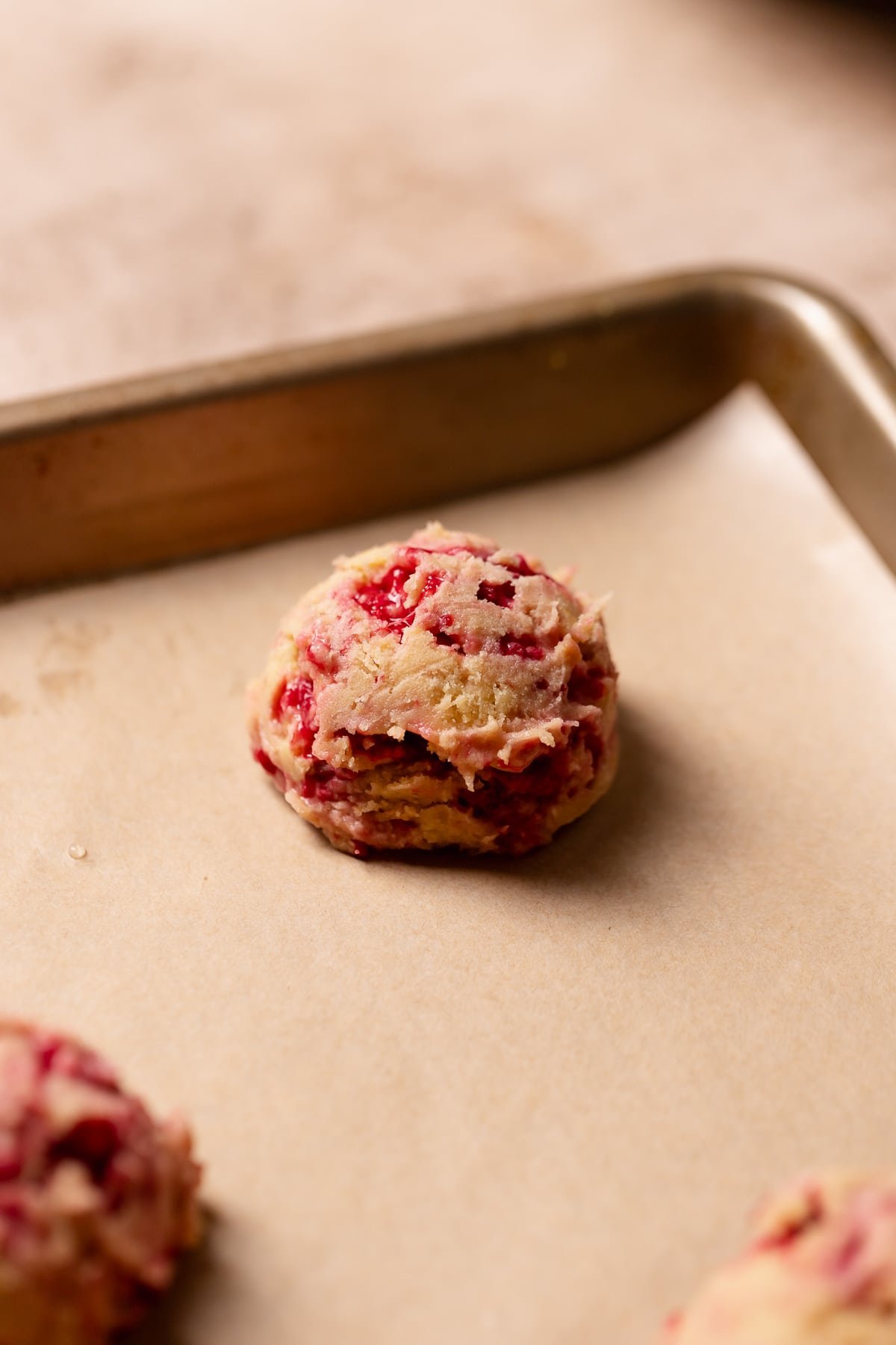 Lemon raspberry cookie dough ball on a baking sheet.