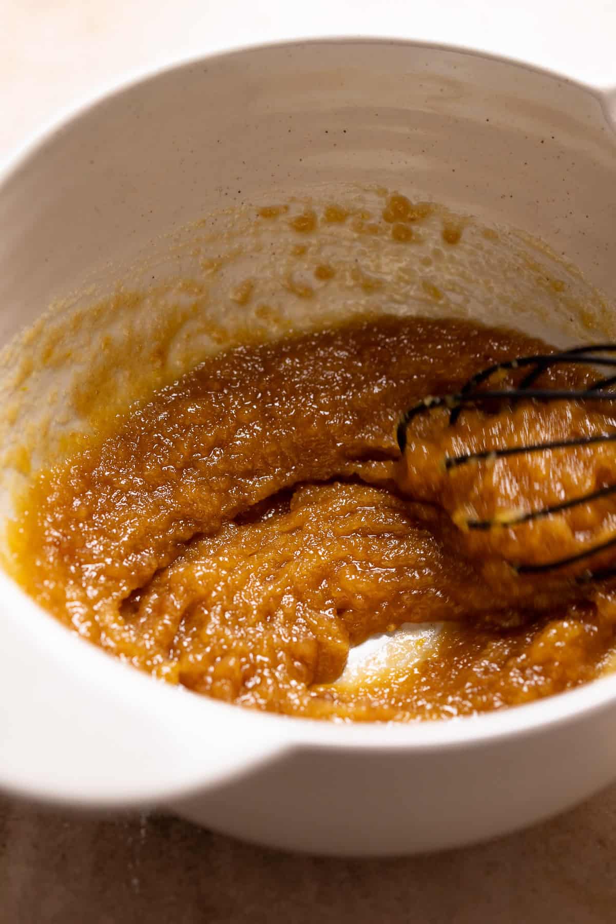 A whisk mixing the butter and sugars together.