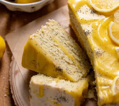 Lemon poppy seed layer cake cut into slices on a wooden platter.