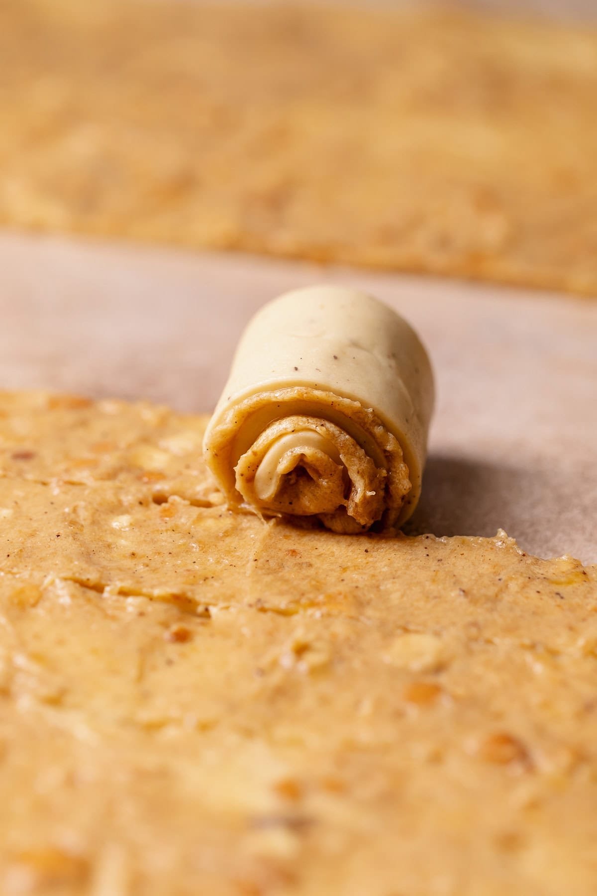 A banana pudding roll being rolled up into a bun.