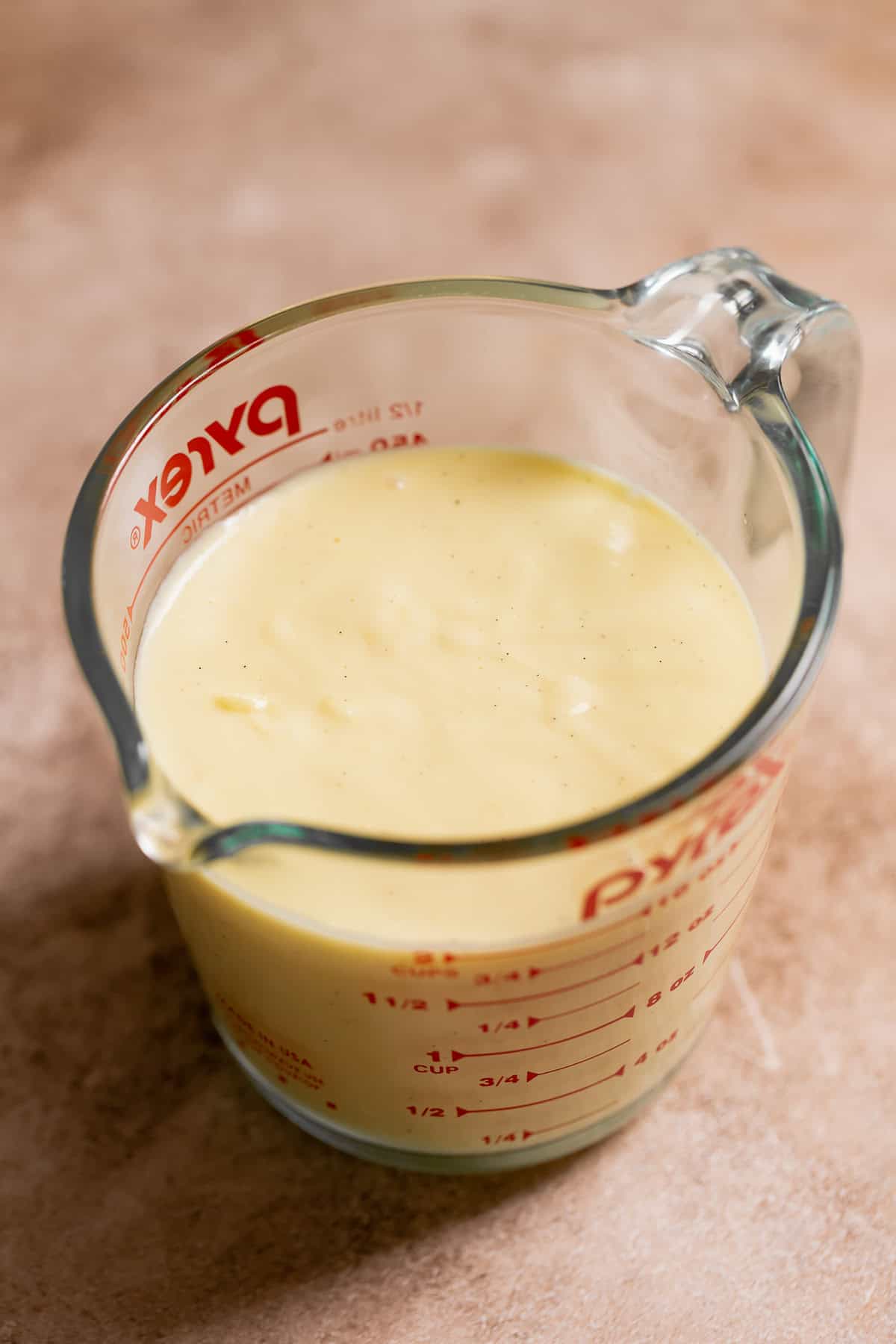 A glass measuring cup full of homemade vanilla pudding.