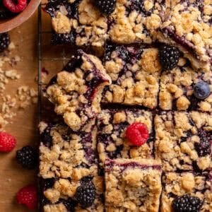 Brown sugar berry crumble bars topped with fresh raspberries, blackberries, and blueberries.