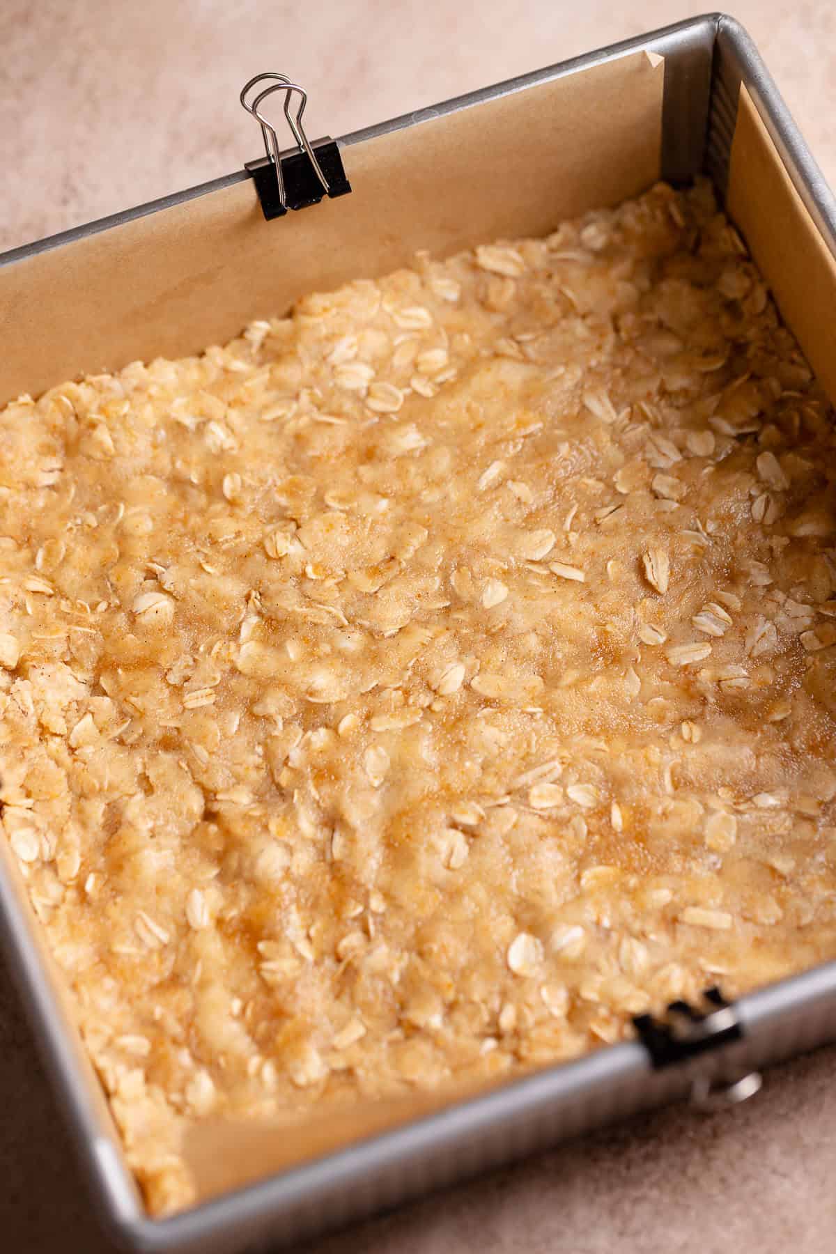 Brown sugar oatmeal crumble dough pressed into a baking pan.
