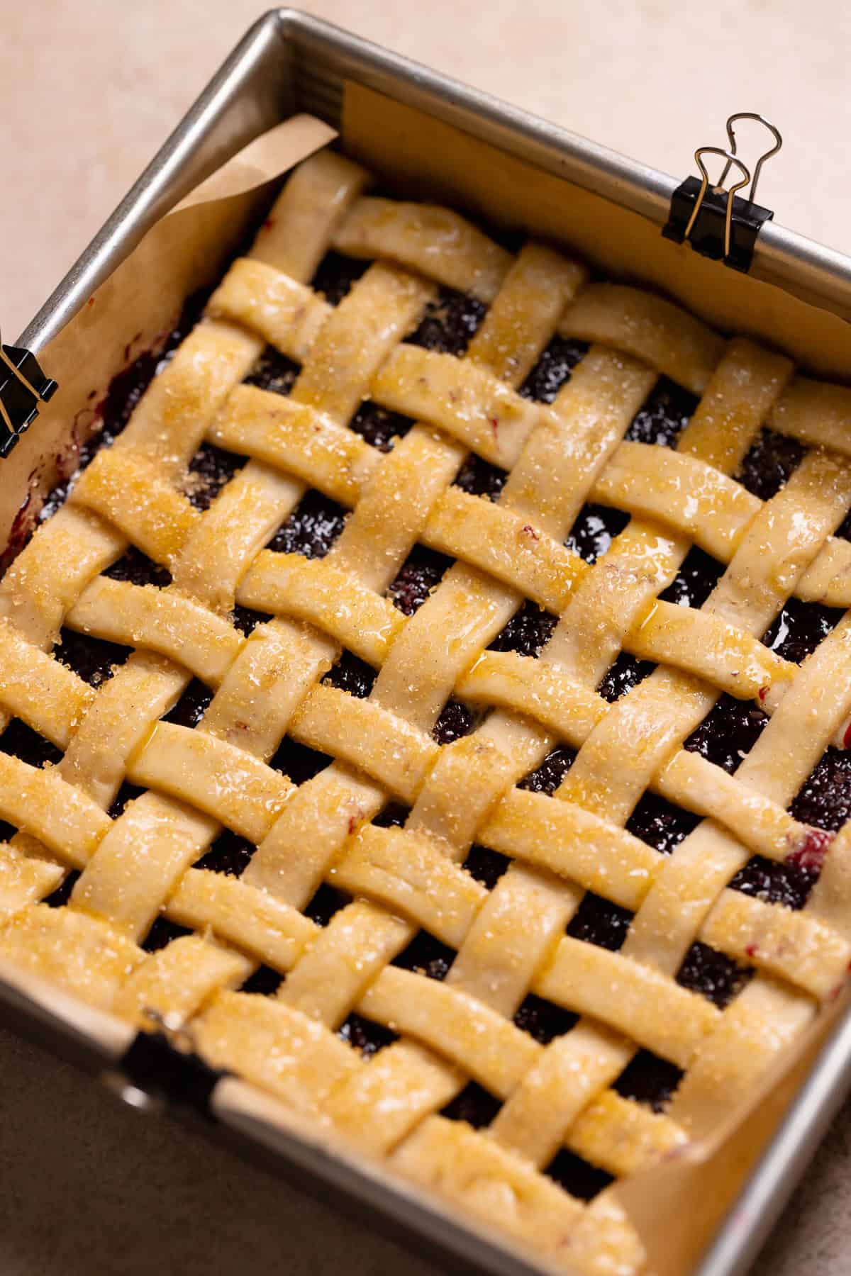 Blueberry bars with pie filling and lattice top in a baking pan before baking.