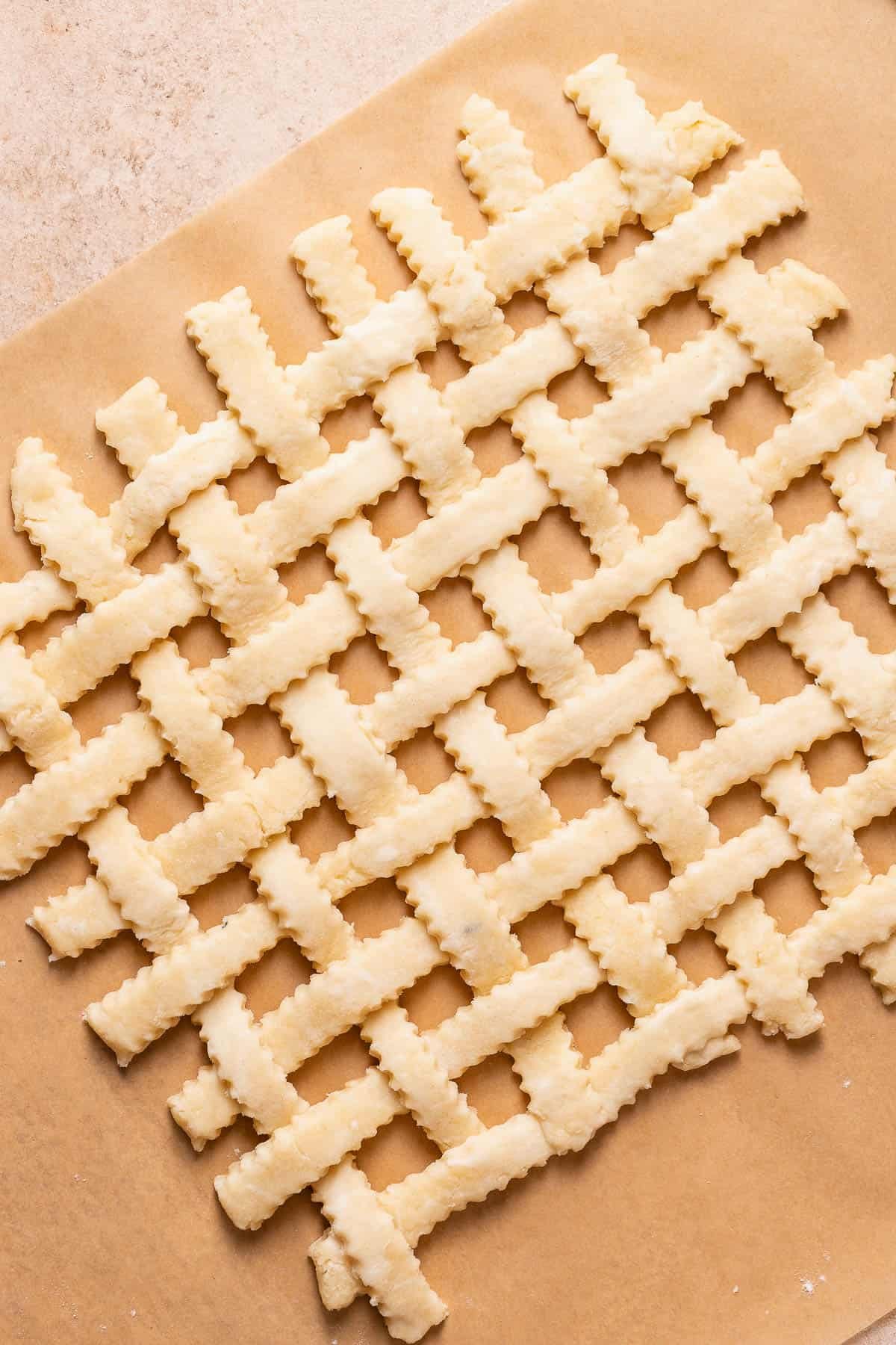 Pie crust strips arranged into a lattice top on parchment paper.
