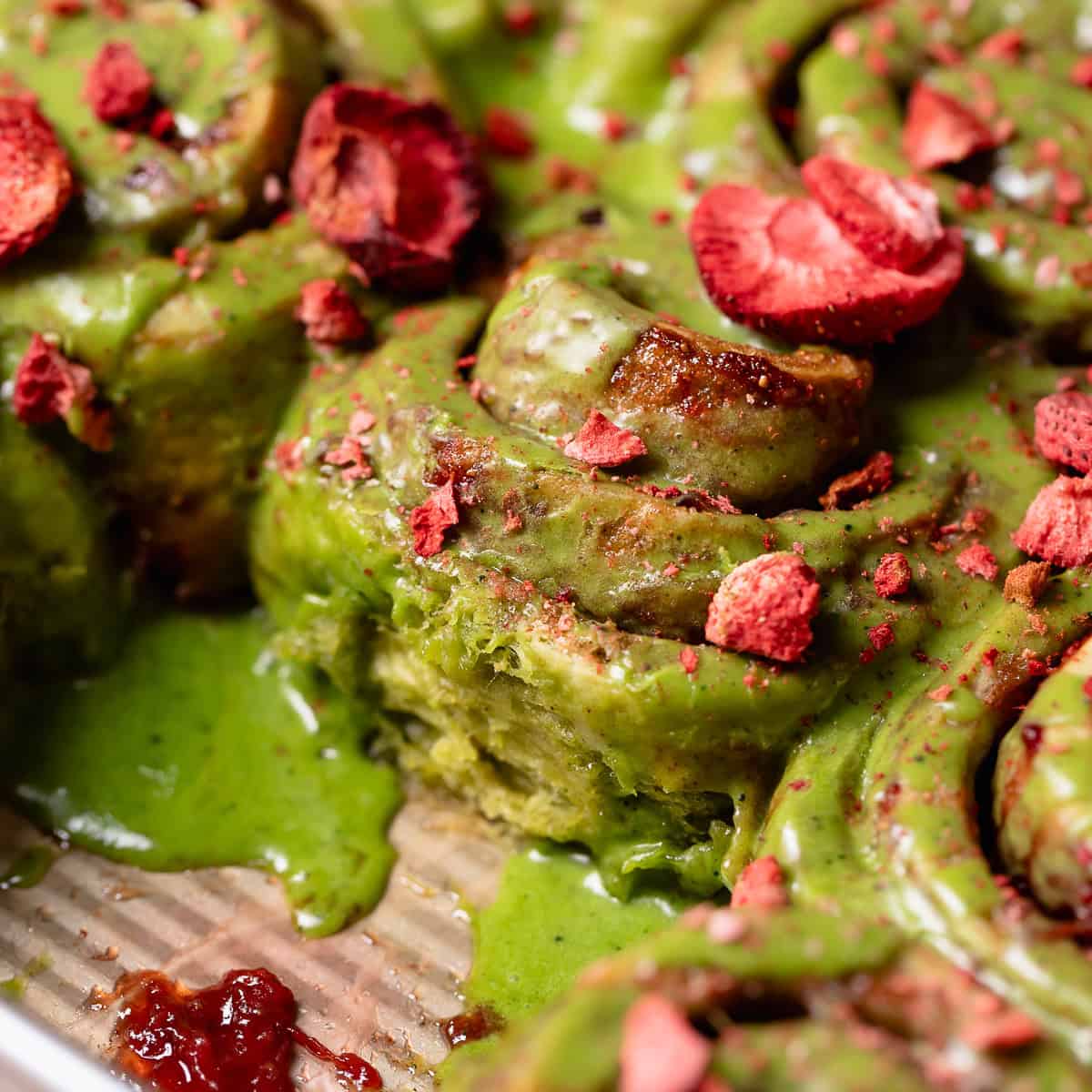 Strawberry matcha cinnamon rolls in a baking pan.