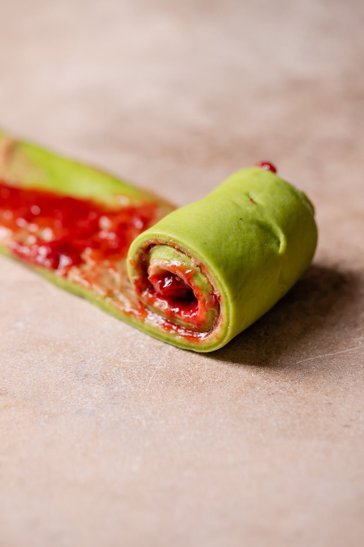 A strip of dough being rolled up into a cinnamon roll.