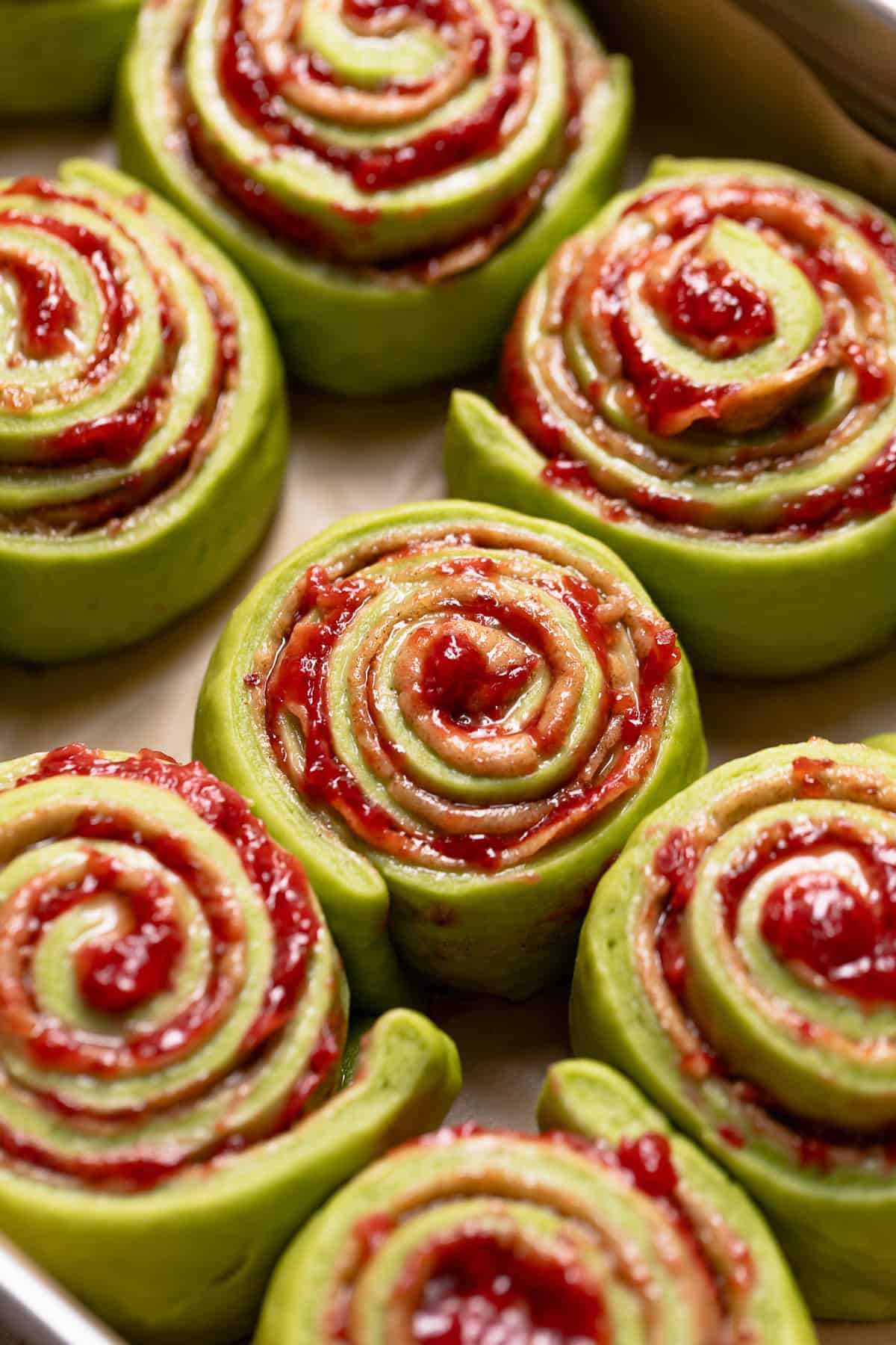 Matcha rolls doubled in size and ready to bake in a baking pan.
