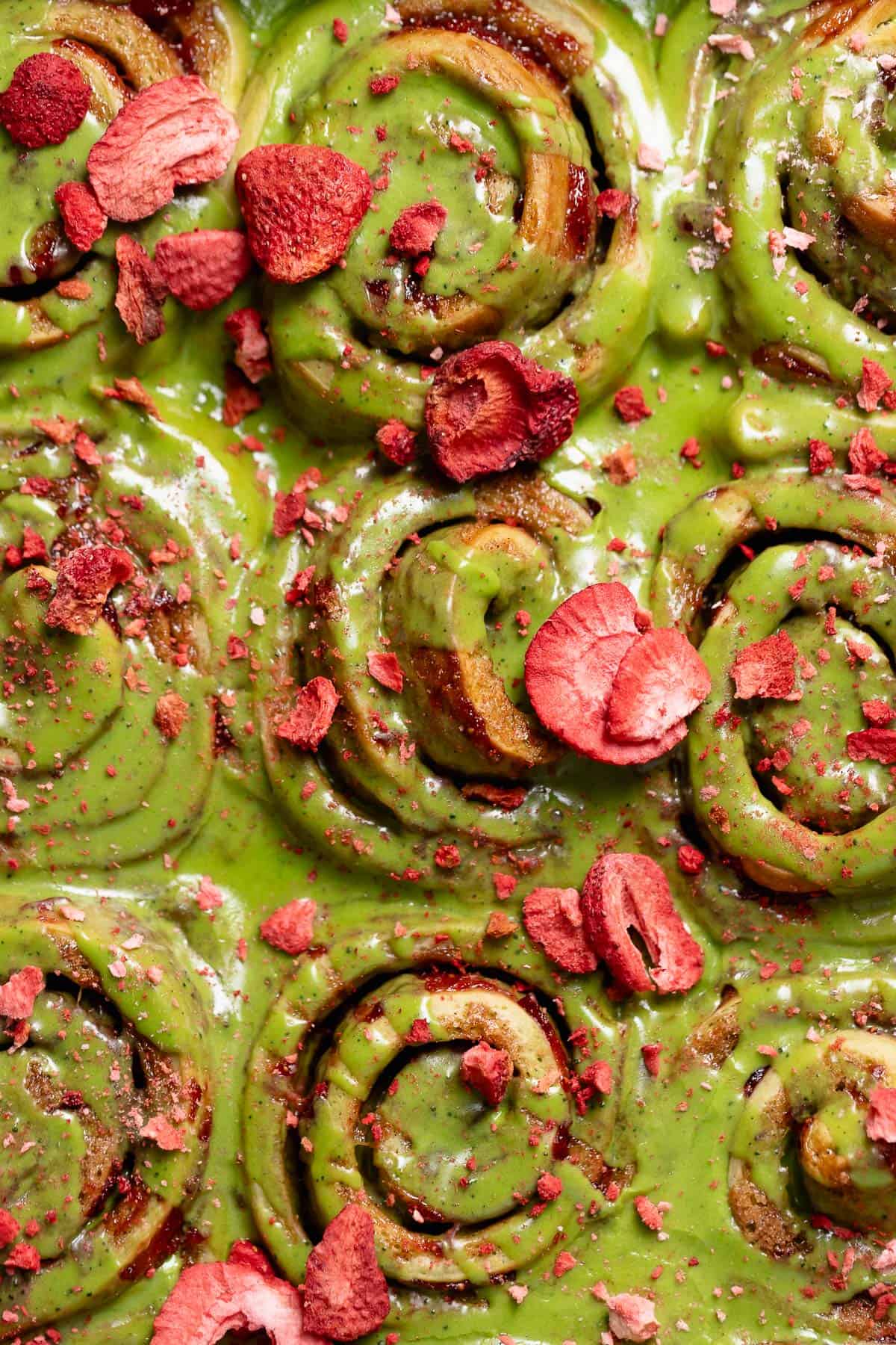 Matcha cinnamon rolls with strawberry filling and freeze dried strawberries on top.
