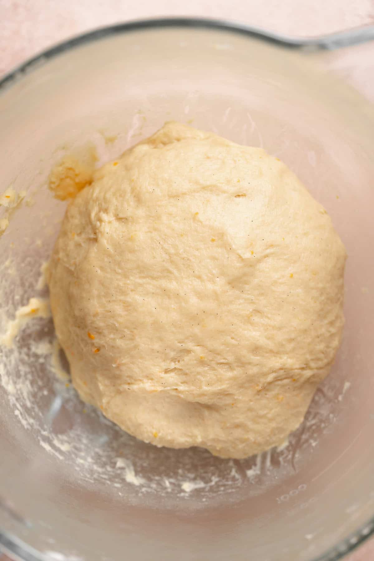 A shaped dough ball resting in a glass bowl.