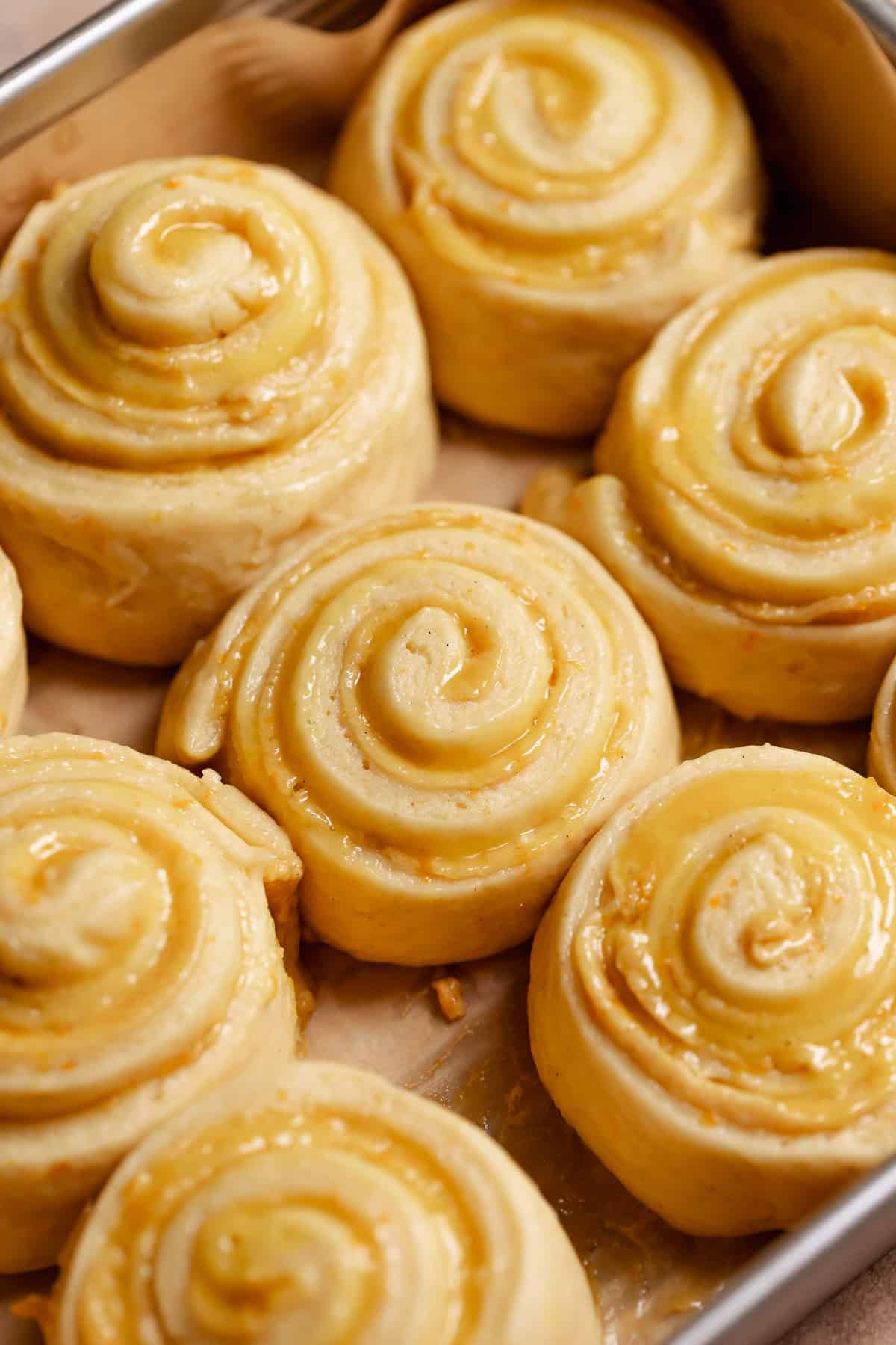 Orange rolls in a baking pan showing they have doubled in size.