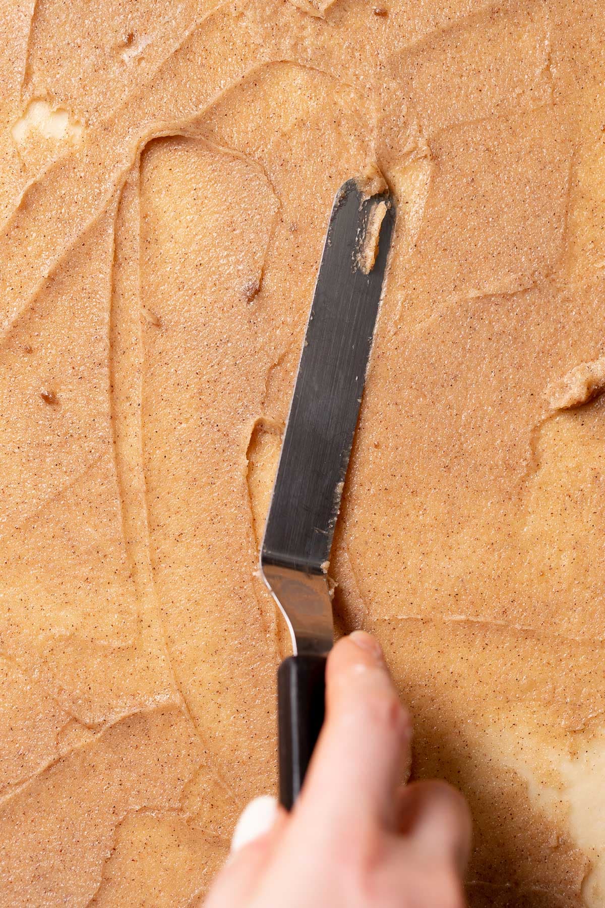 Spreading the cinnamon sugar mixture across the dough.