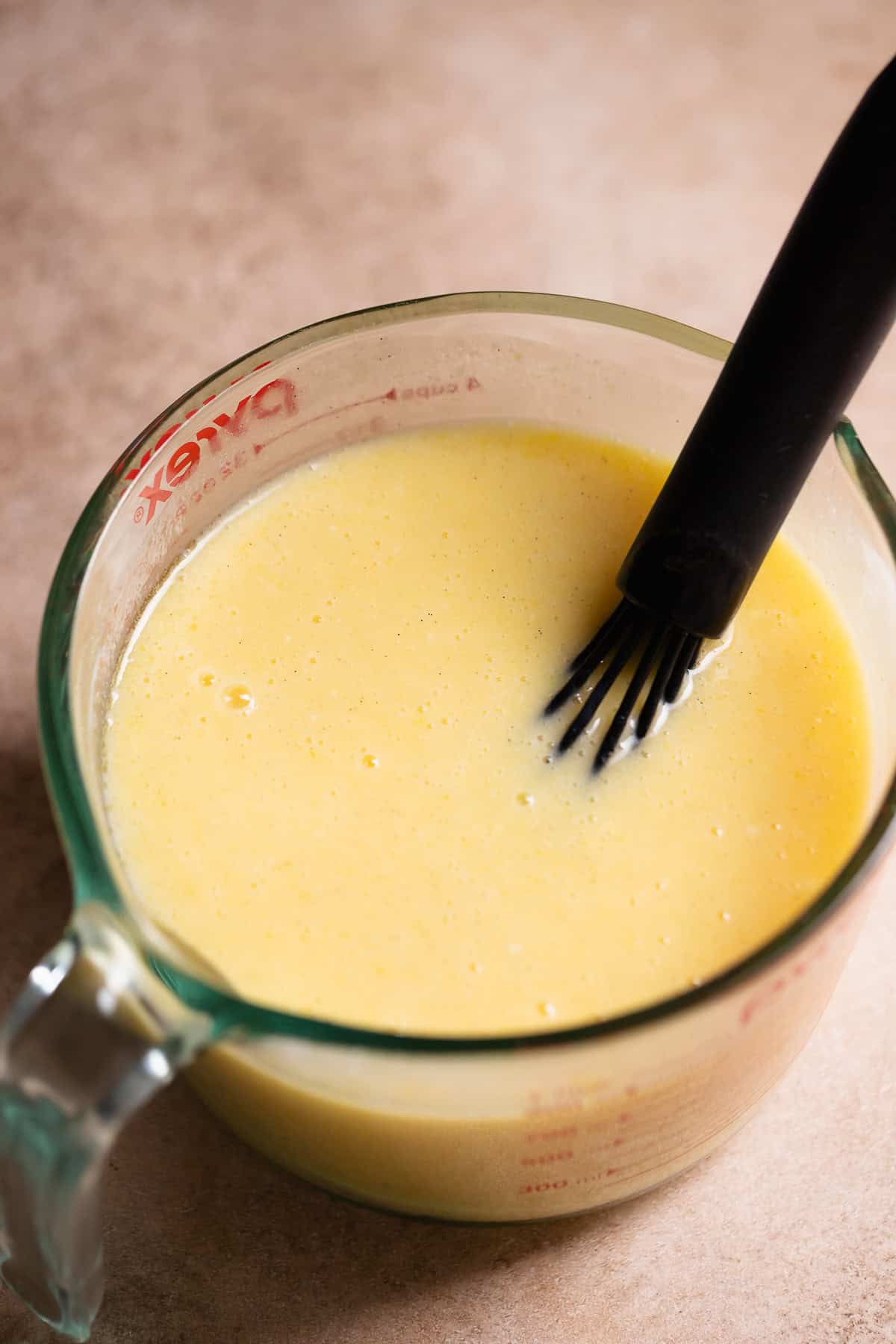 Wet ingredients whisked together in a glass measuring cup.