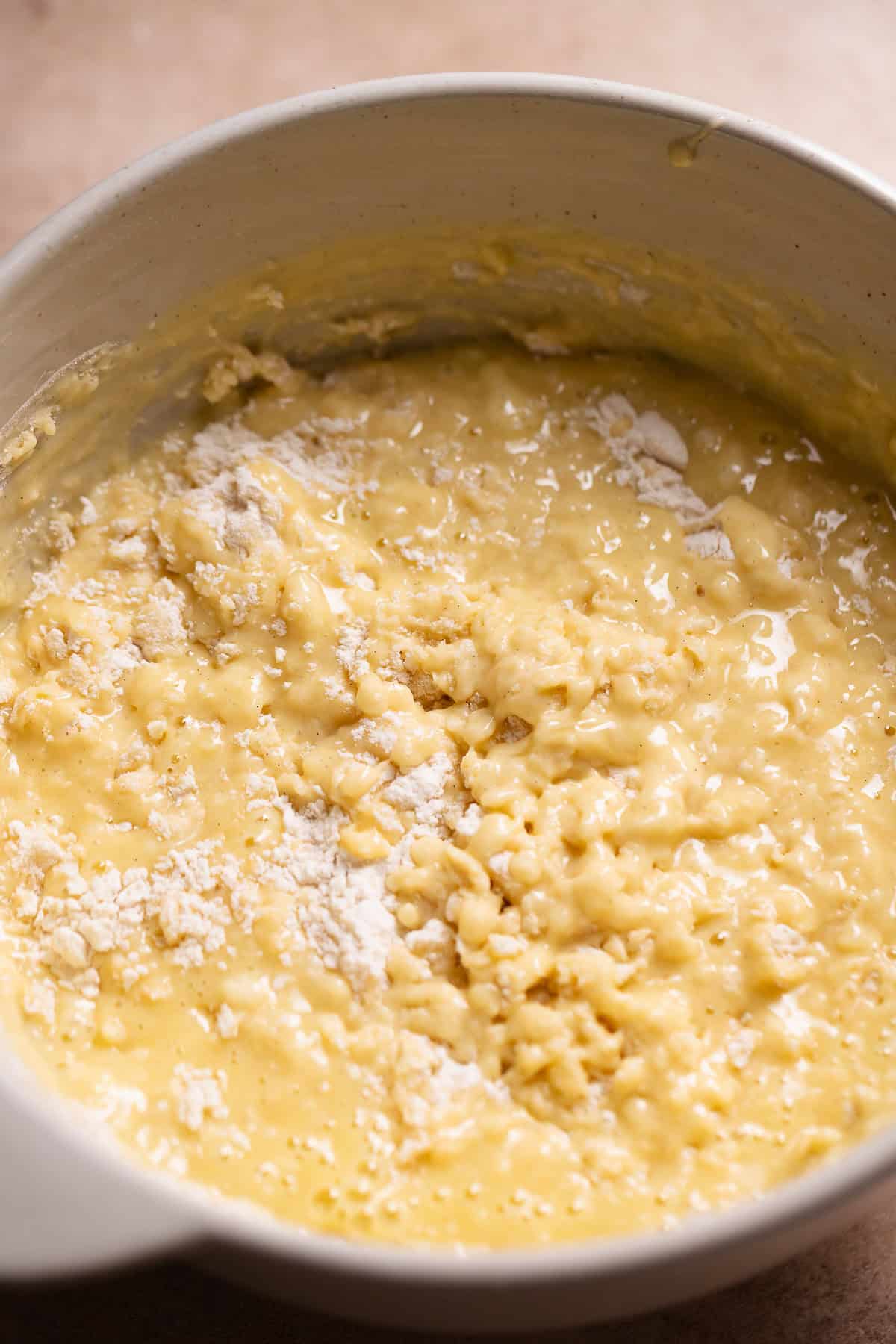 The whisked wet and dry ingredient batter in a bowl with some flour streaks remaining.