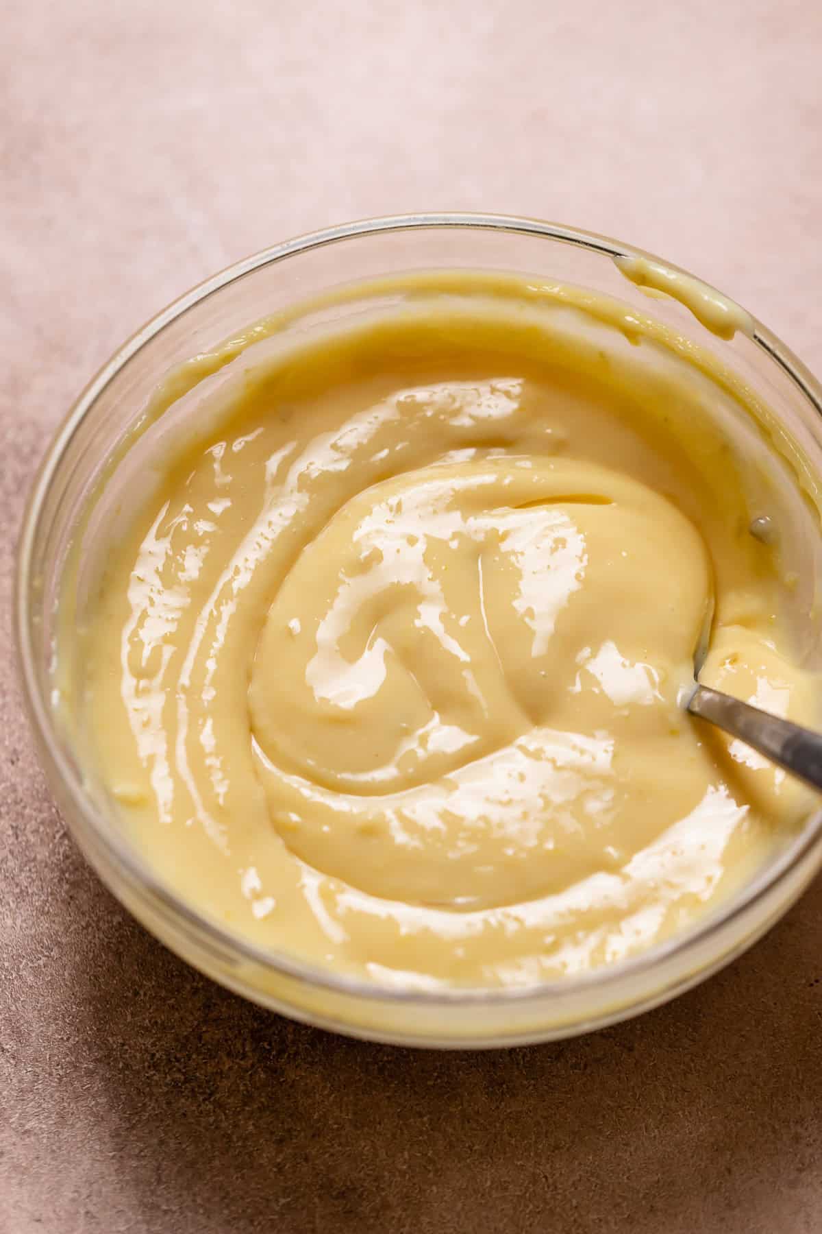 Key lime pie filling in a glass bowl with a spoon.