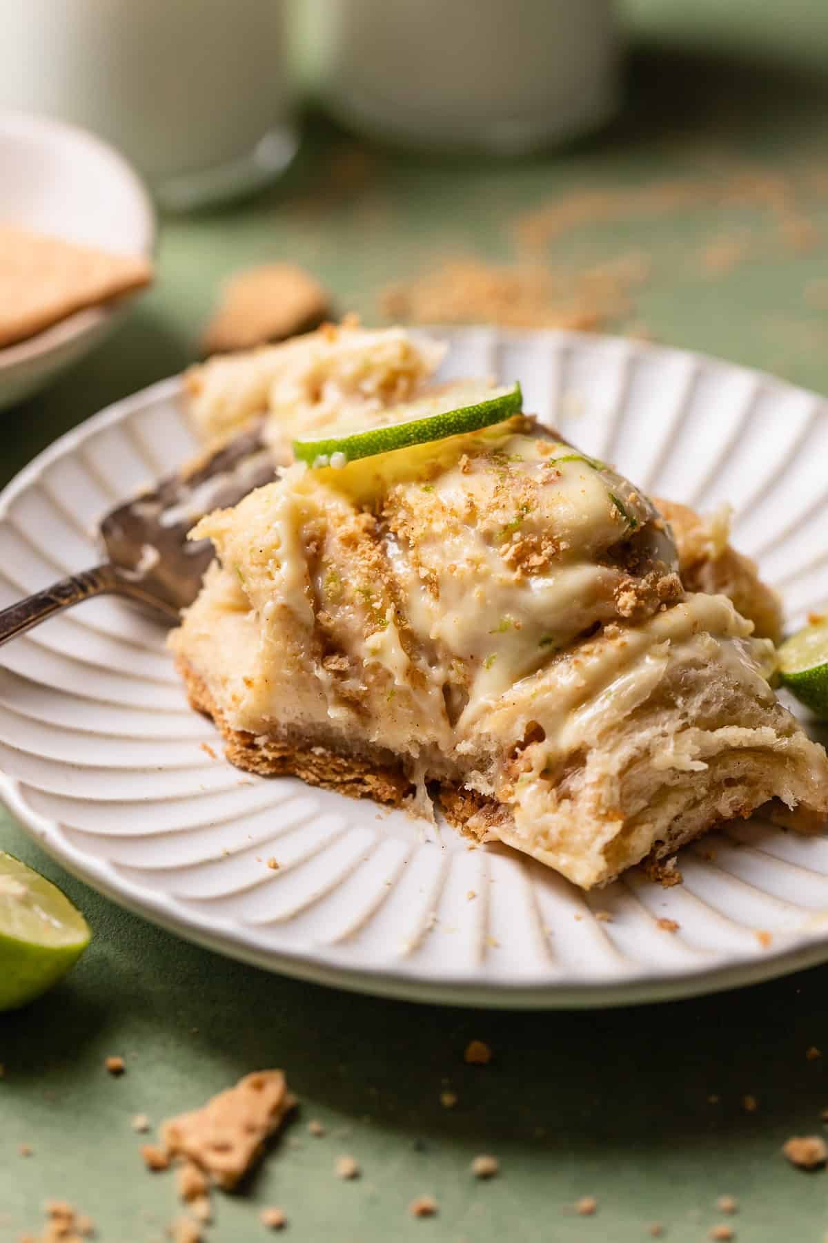 A key lime pie roll with a bite taken out of it on a white plate.