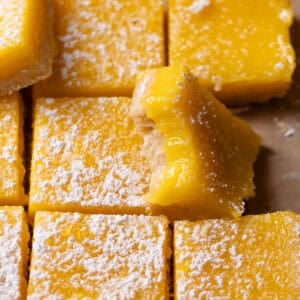 Lemon bars dusted with powdered sugar with one missing a bite.