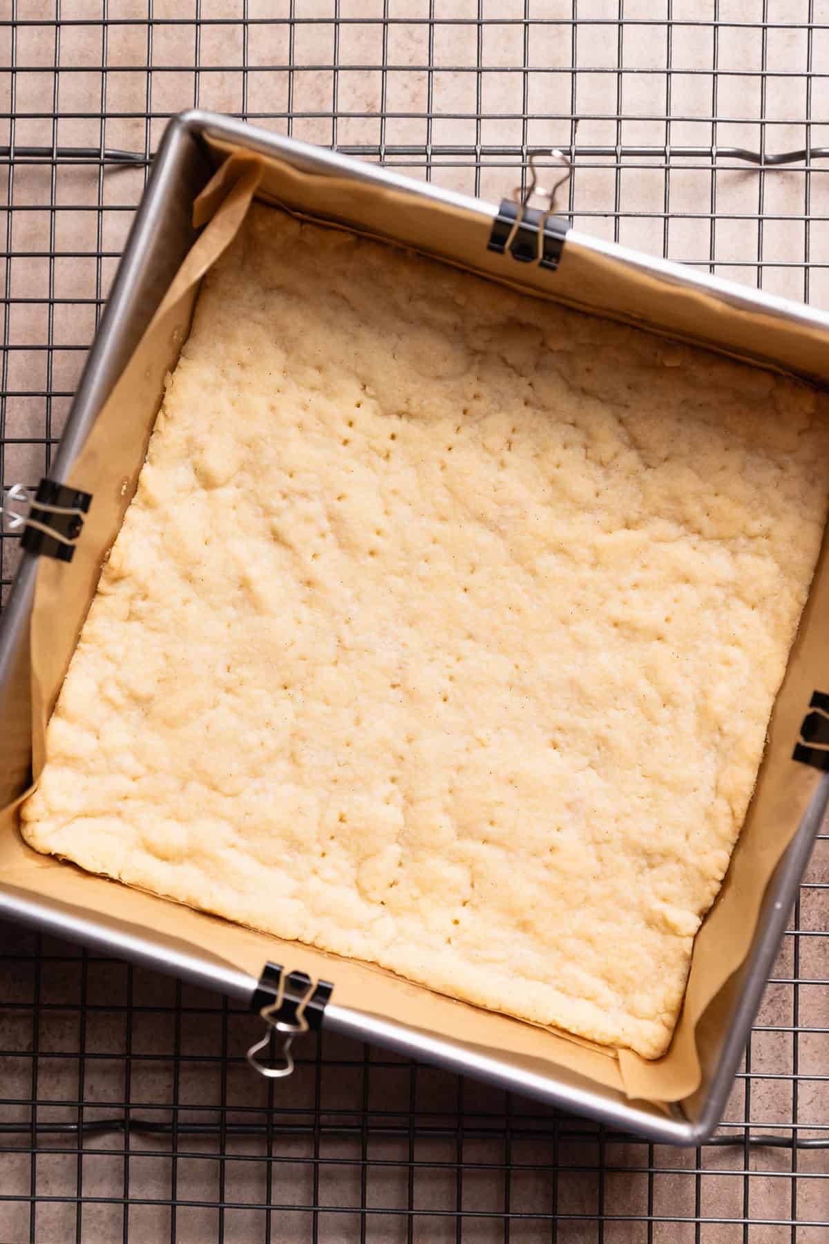 A pan with the baked shortbread crust cooling on a wire rack.