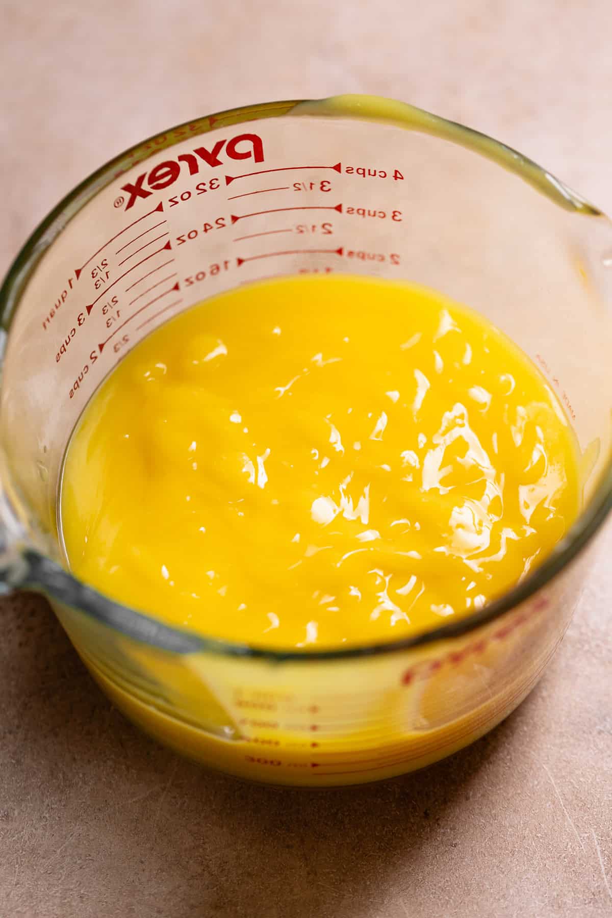 Lemon curd in a glass measuring cup.
