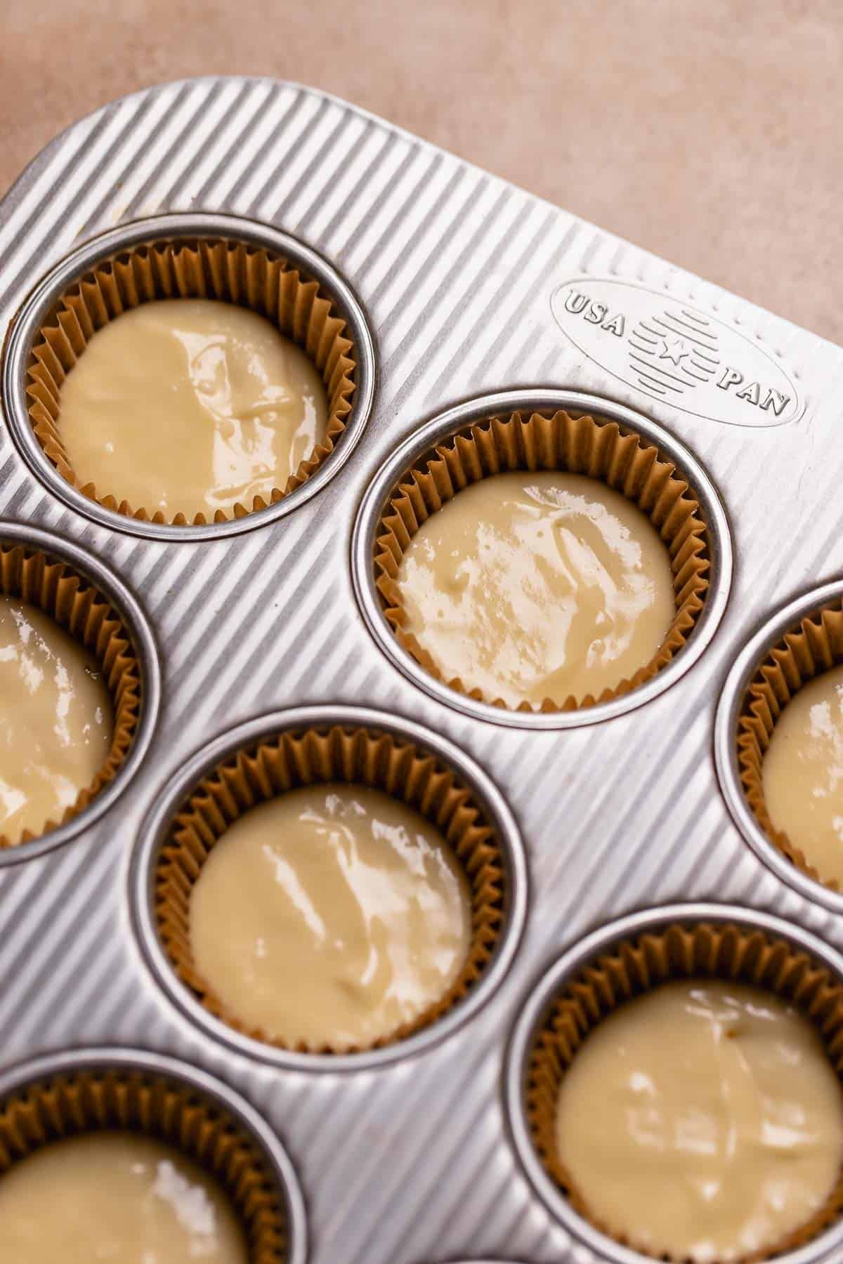 Lemon cupcake batter filled cupcake liners in a pan.