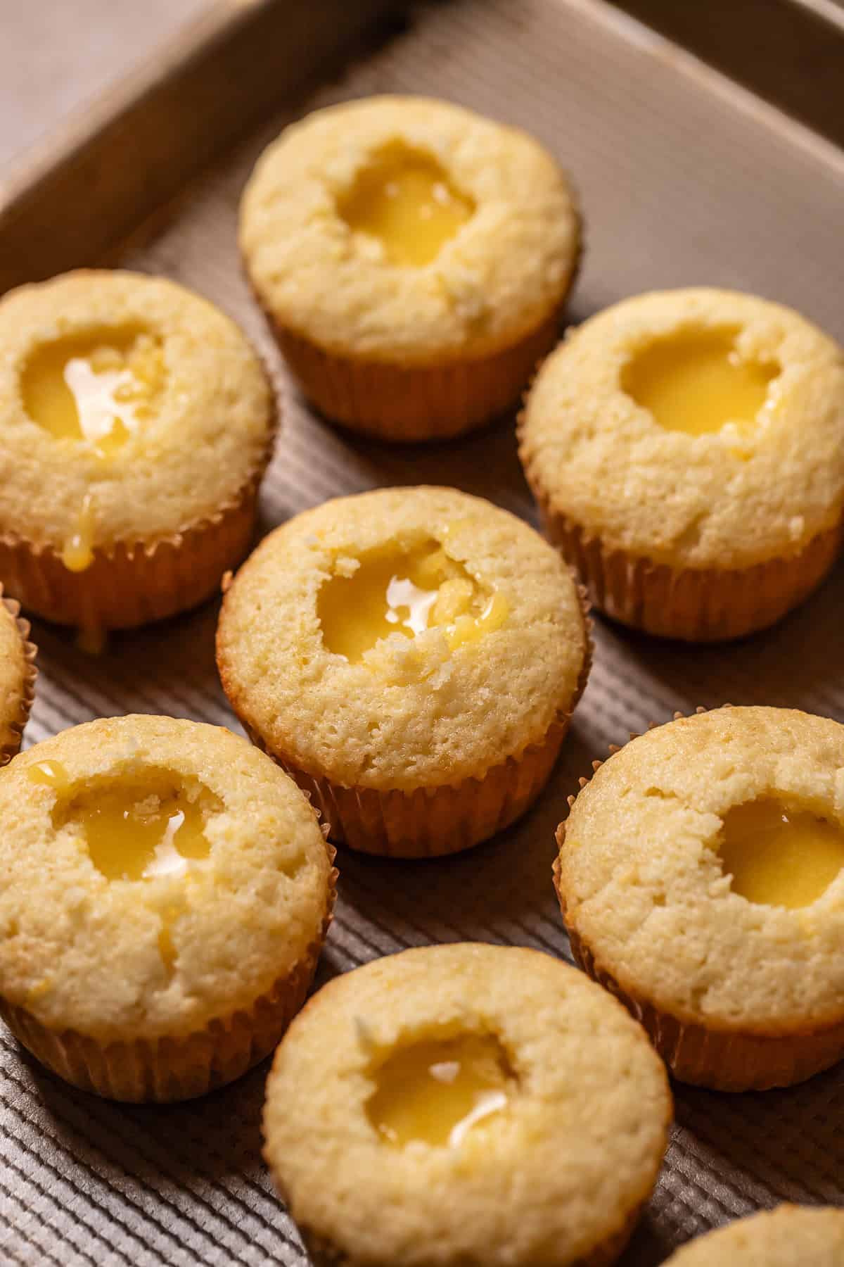 Lemon cupcakes filled with lemon curd on a baking pan.