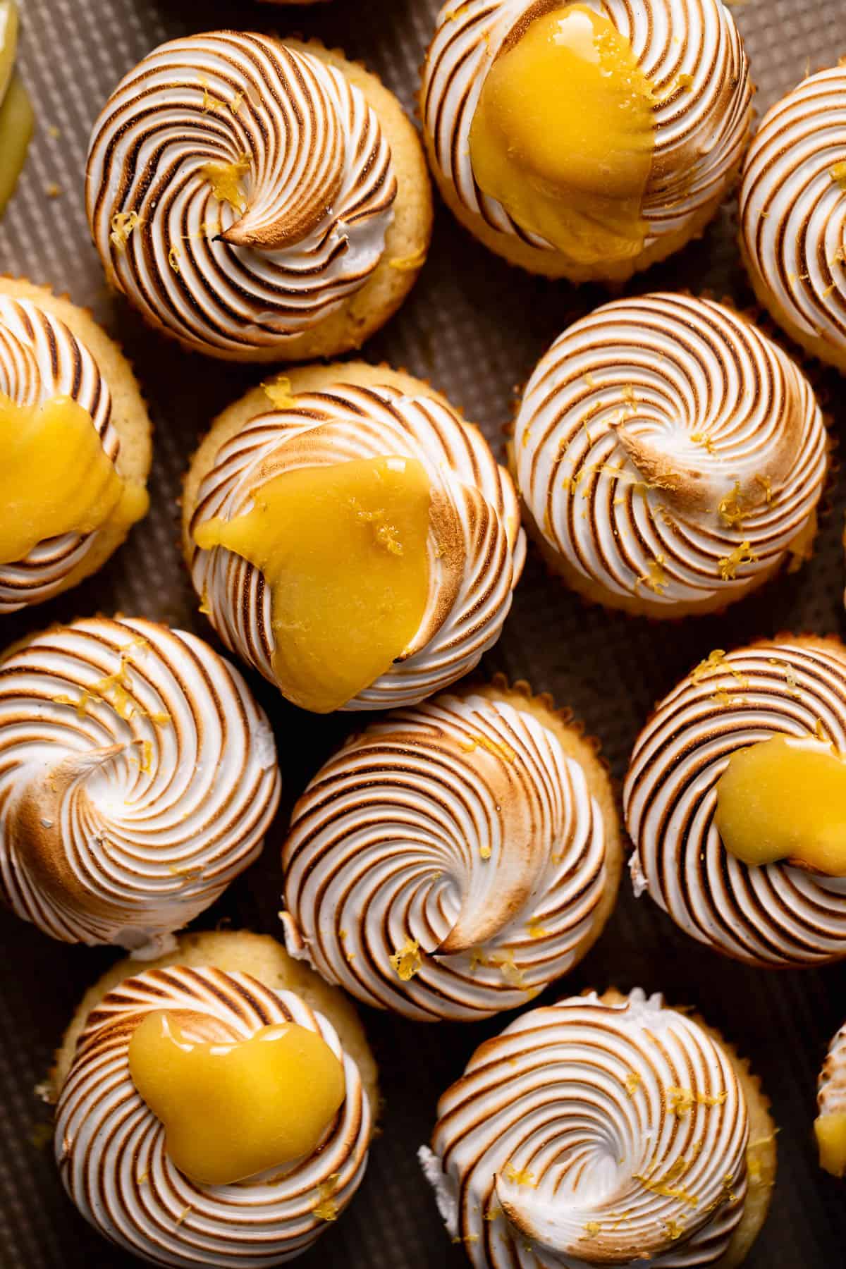 An overhead shot of lemon cupcakes with torched meringue frosting and lemon curd on top.