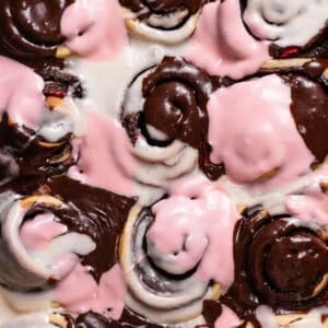 Neapolitan roll in a baking pan with tri-colored icing.