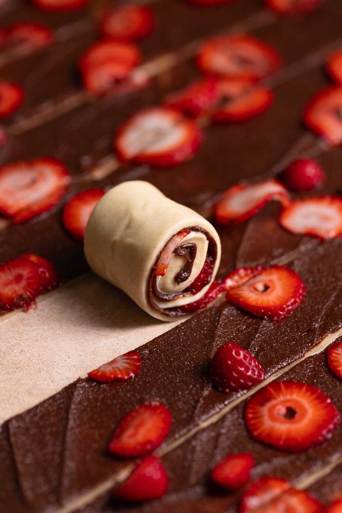 A strip of cinnamon roll dough being rolled up.