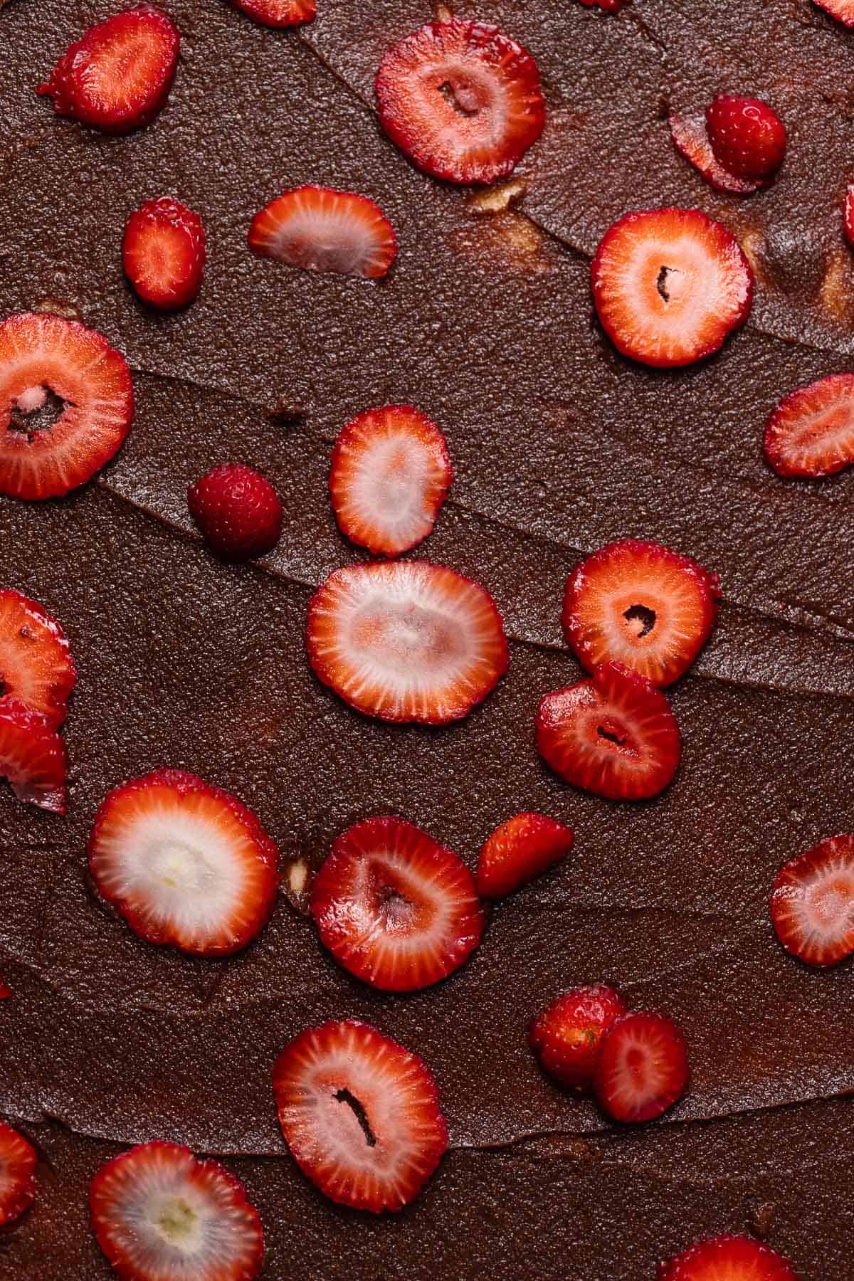 Chocolate filling spread across the cinnamon roll dough with fresh sliced strawberries scattered on top.