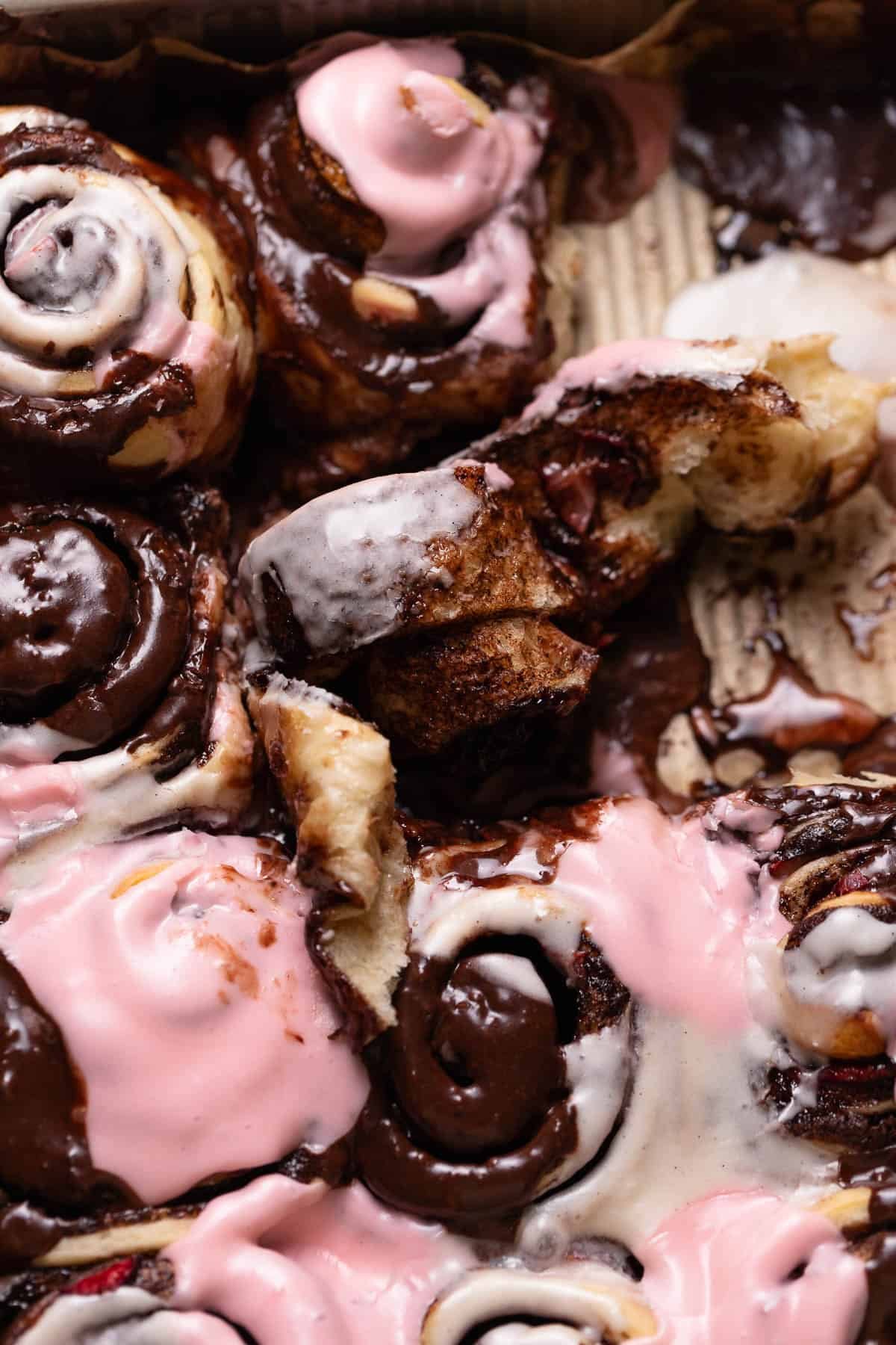 A cinnamon roll half unrolled in the baking pan to show the gooey center.